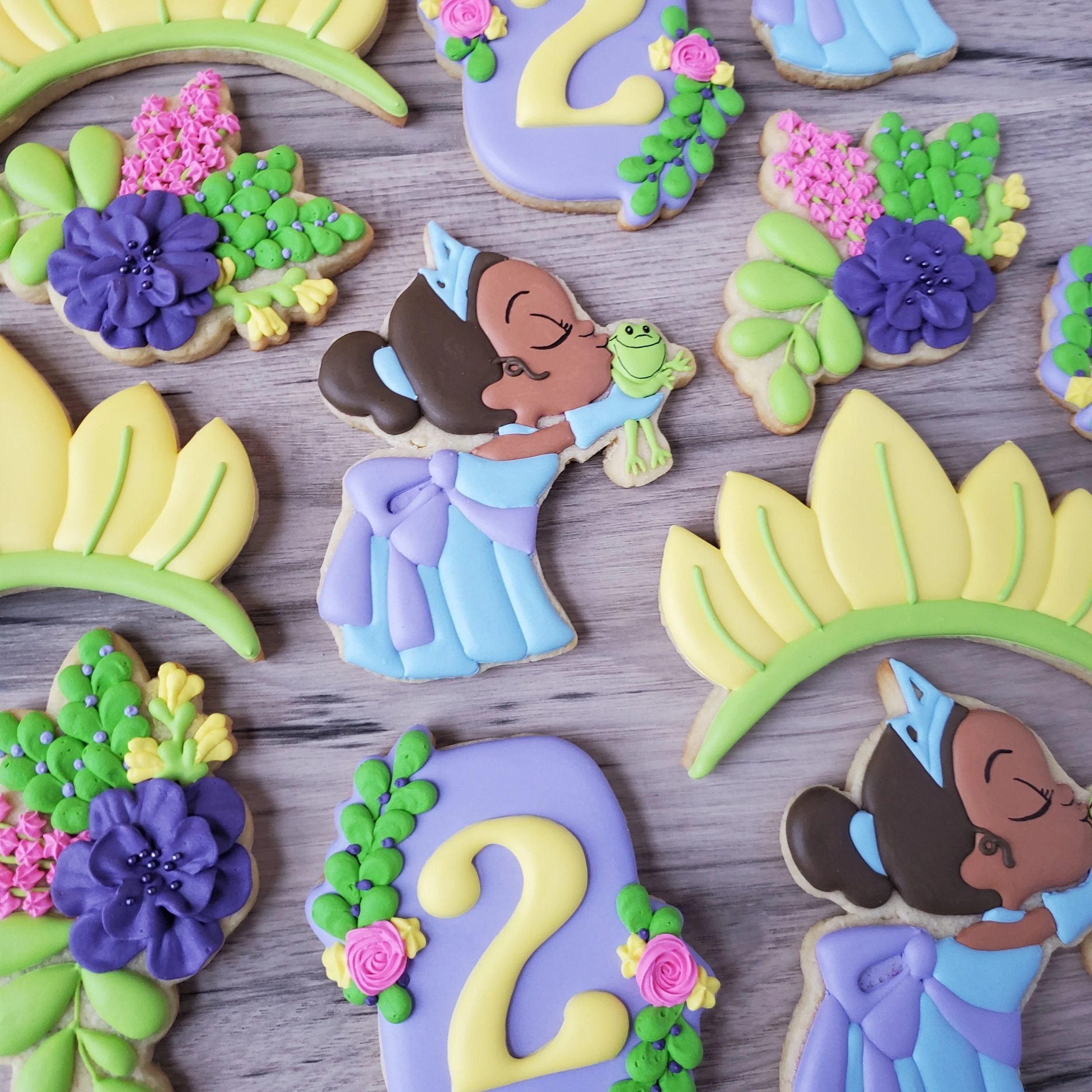 Decorated cookies themed for a celebration, featuring princess and floral designs, with pastel colors and the number 2.