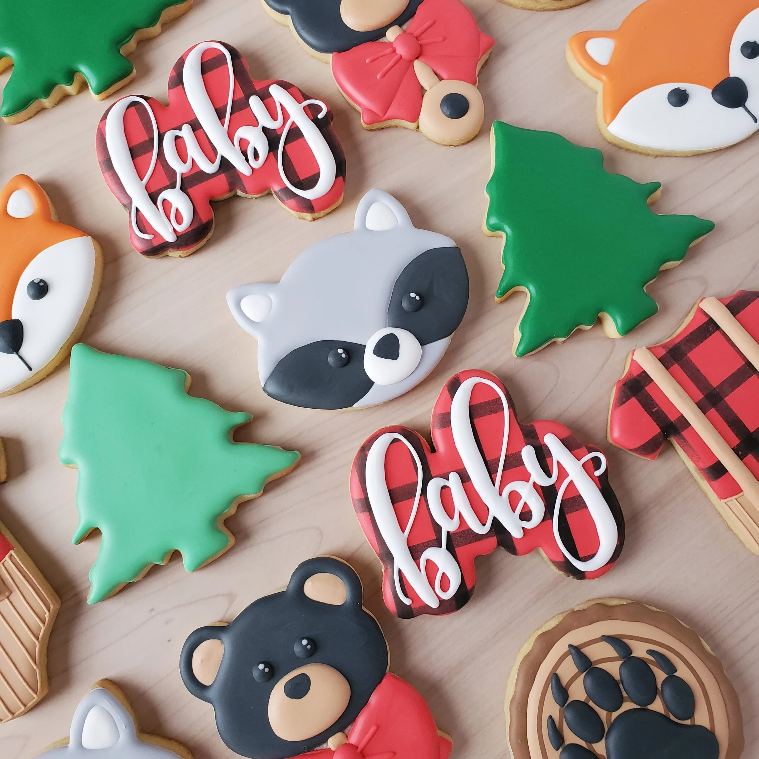 Assorted decorated cookies with a Christmas theme, including trees, animals, and the word 'baby' written on a cookie.