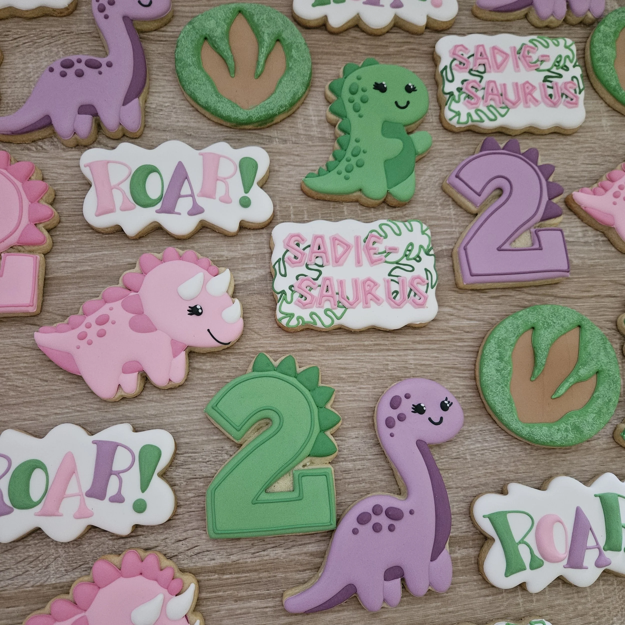 Colorful dinosaur-shaped decorated cookies with words like "ROAR" and 