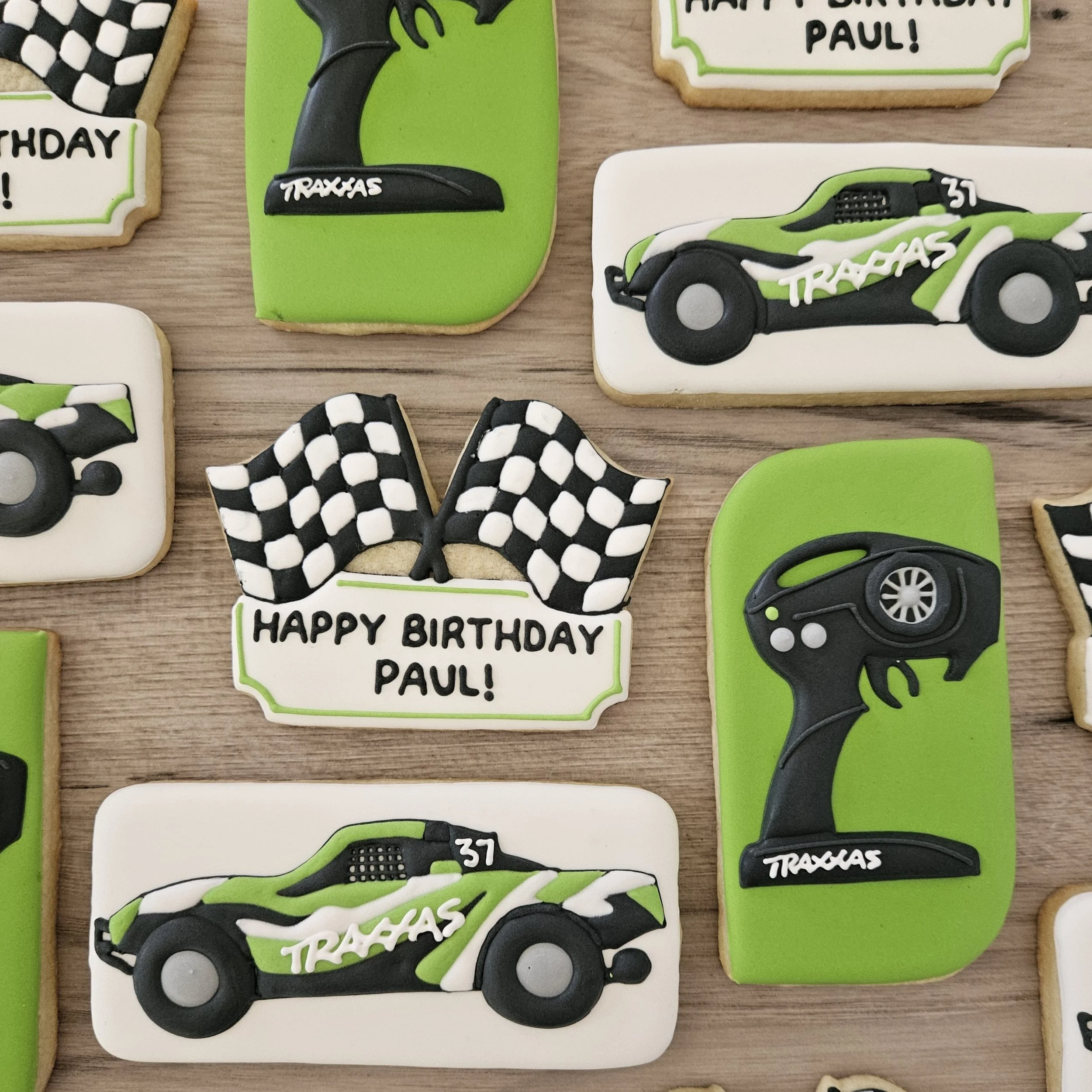 Cookies decorated with race car, checkered flags, and remote control themes, with inscriptions like "Happy Birthday Paul!"