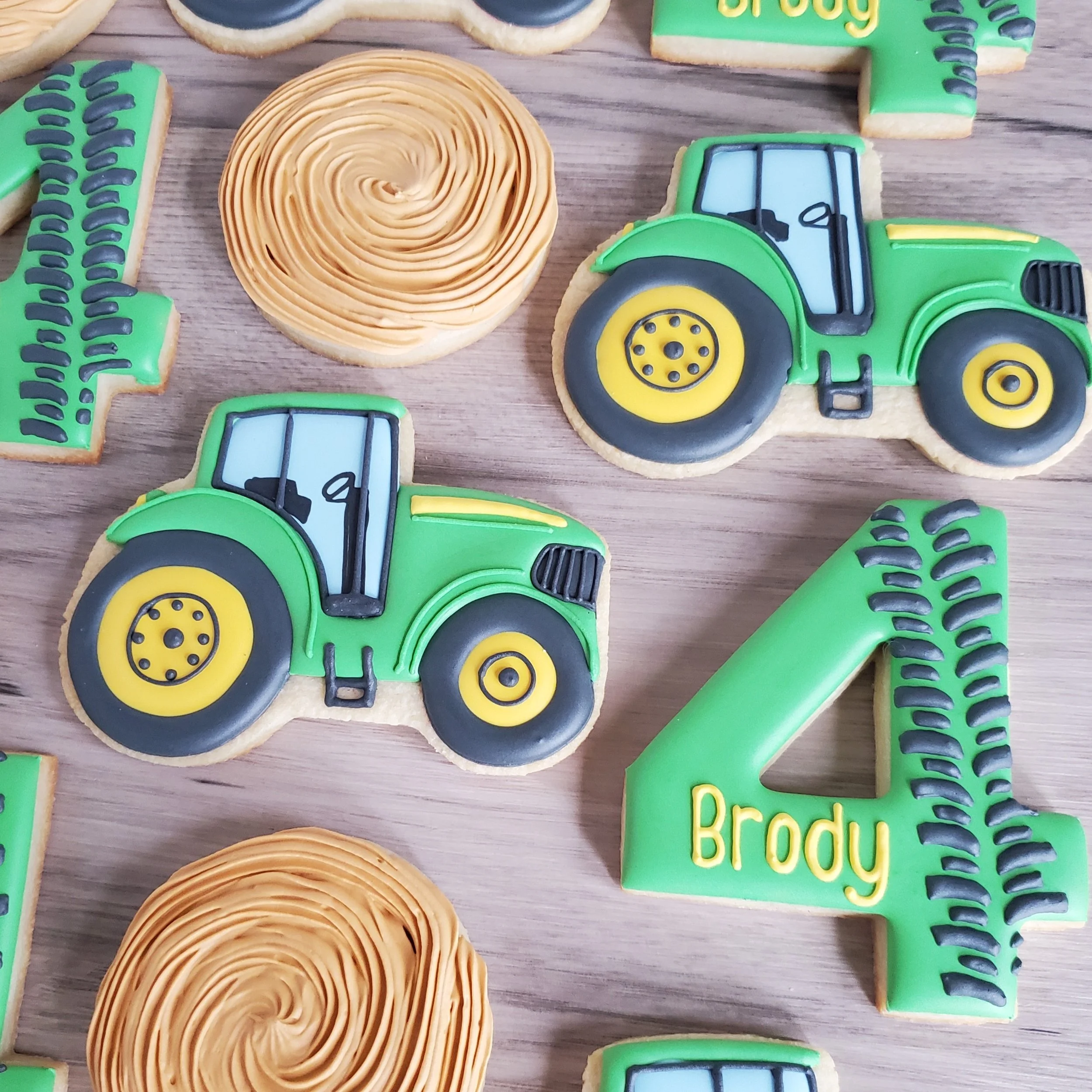 Decorative cookies with green tractor and large number 4, personalized with the name Brody, on a wooden surface.