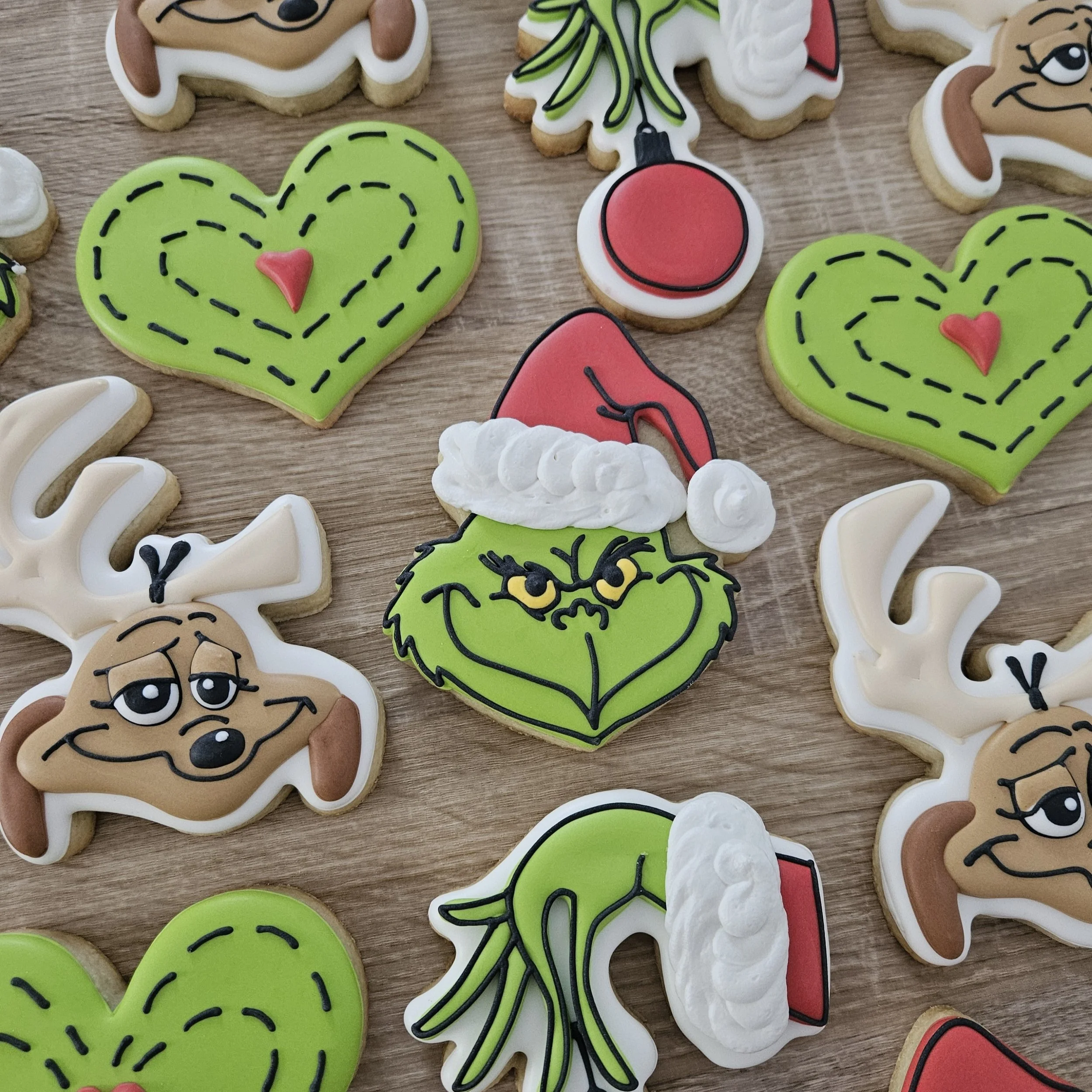 Decorated cookies featuring Dr. Seuss characters, hearts, and holiday themes on a wooden surface.