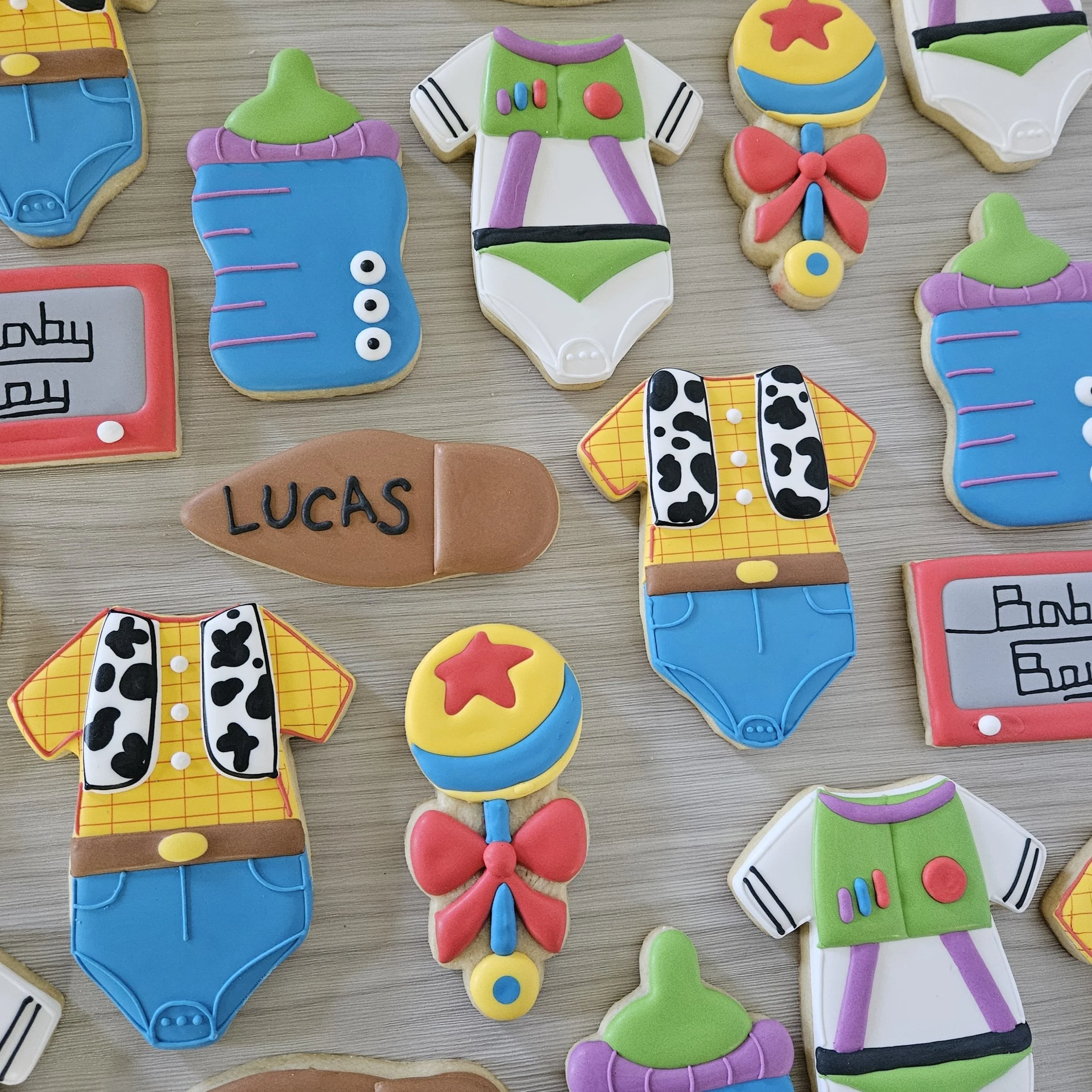 Decorated sugar cookies with Toy Story theme, including Sheriff Woody and Buzz Lightyear outfits, a ball, a speech bubble, and a labeled cookie that says "LUCAS."