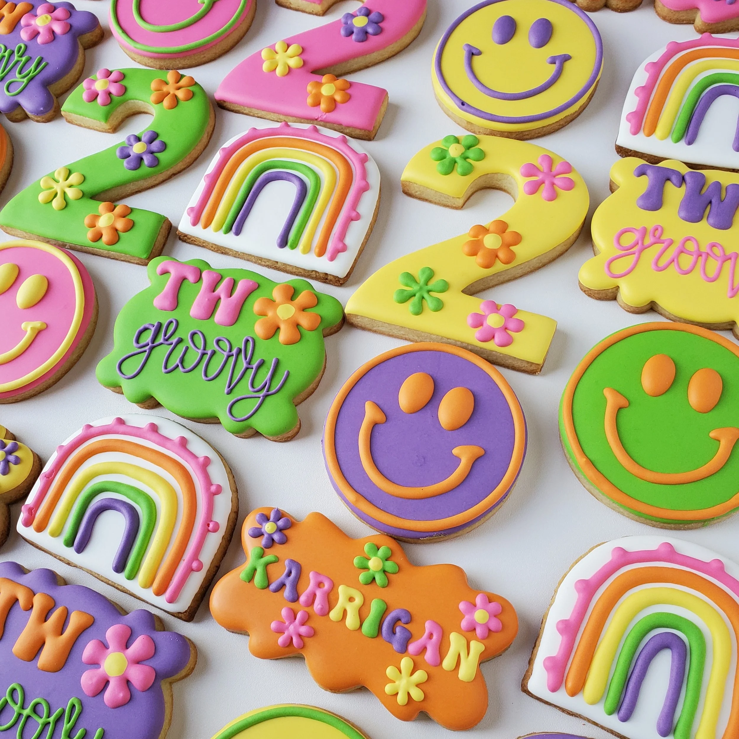Colorful decorated cookies with smiley faces, rainbows, and the phrases 'THW growy' and 'KARRIGAN' in pastel colors.