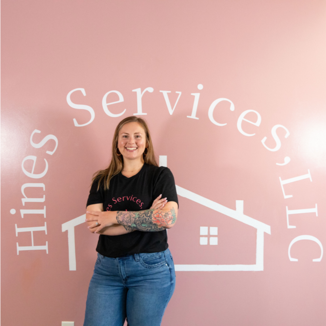 The owner of Hines Services LLC posing in front of her logo and happy that she has an operations team
