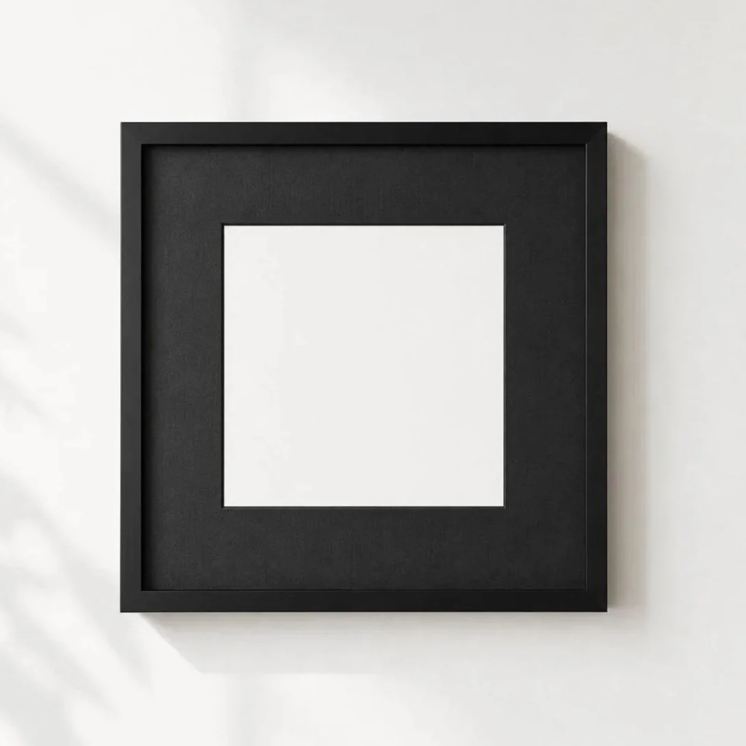 Cuadro negro con marco negro, vacío en una pared blanca.
