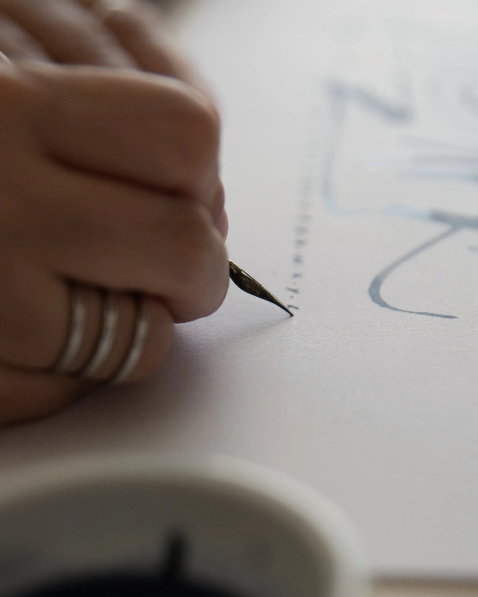 Primer plano de una pluma realizando trazos gestuales sobre papel blanco.