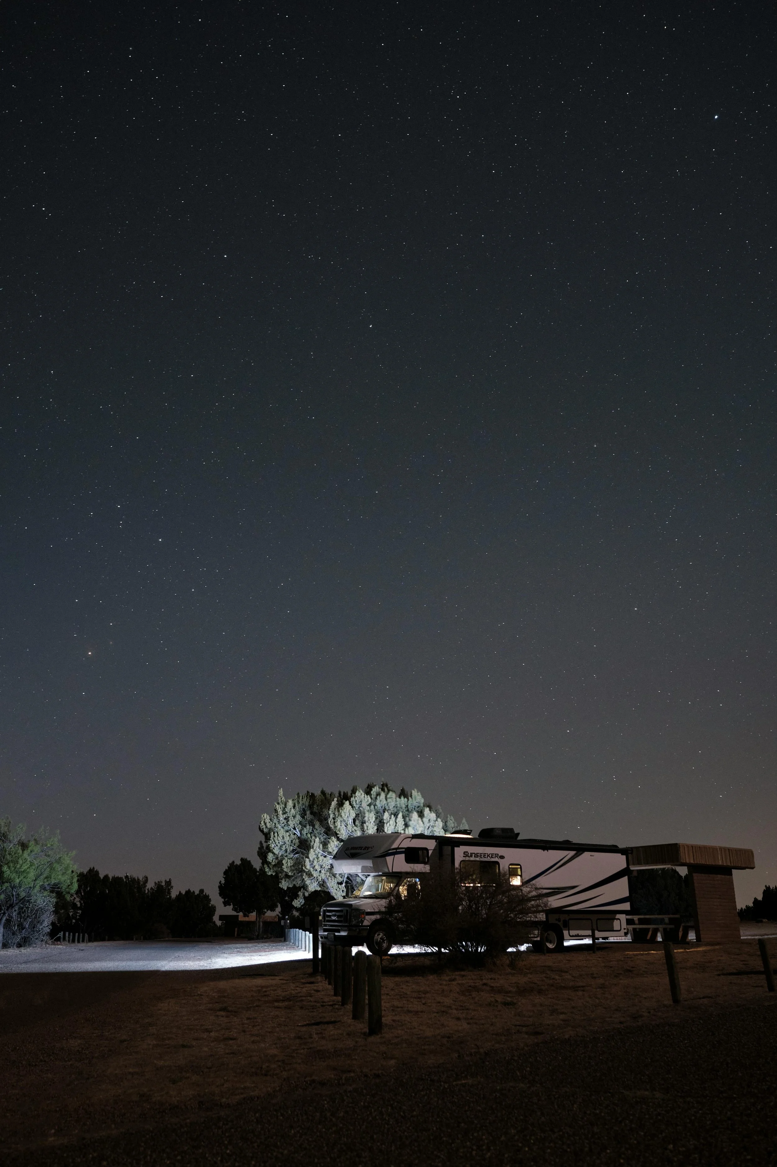 RV parked at a quiet campground at night under a clear starry sky