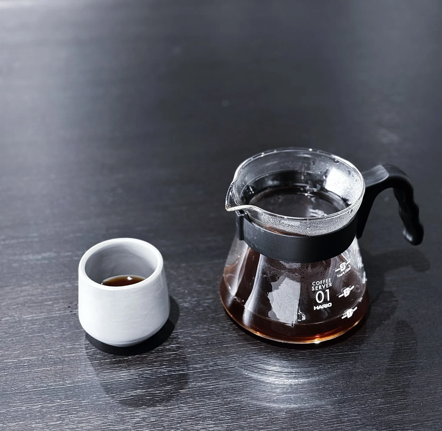 A person wearing a hoodie, glasses, and a backpack, walking and holding a steaming cup.