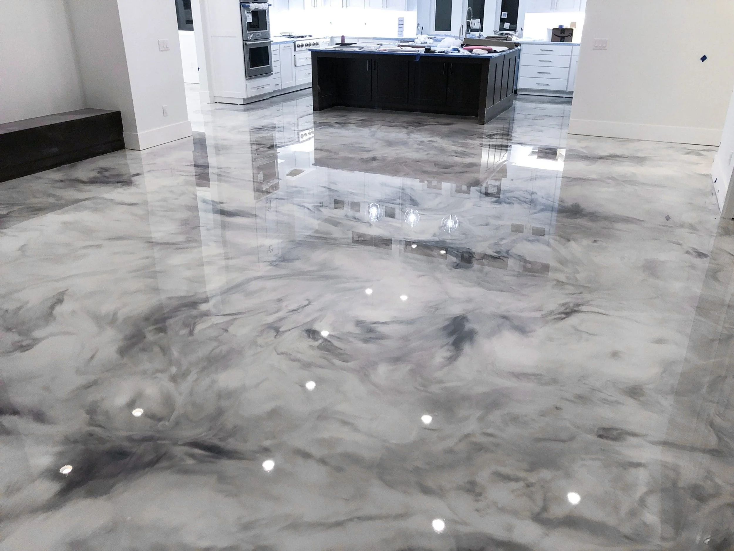 A modern kitchen with a shiny marble floor, white and dark cabinetry, and stainless steel appliances.