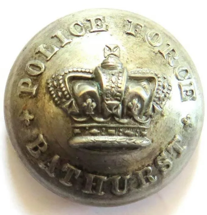 Close-up of a circular metallic badge with the inscription 'POLICE OF BALTIMORE' and an embossed crown symbol in the center.