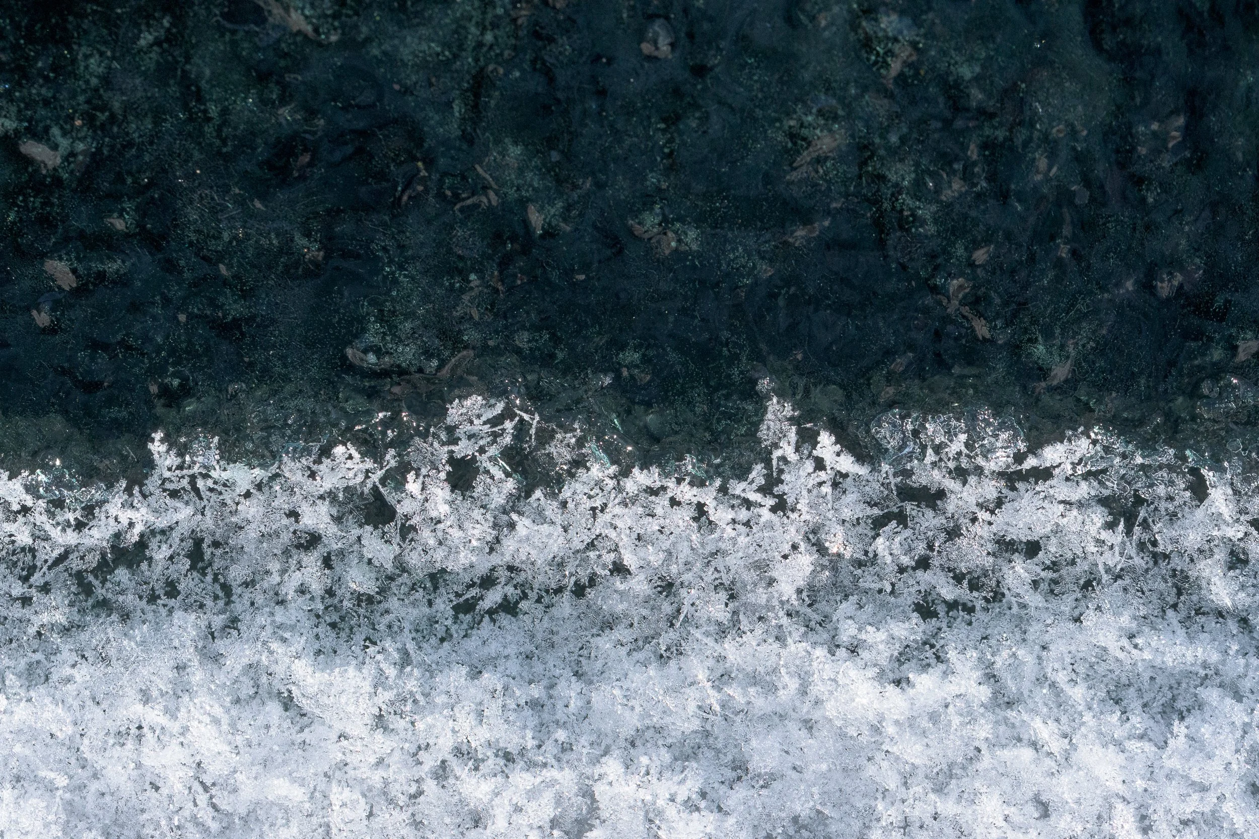 Close-up of a dark, icy surface with snowflake patterns at the bottom.