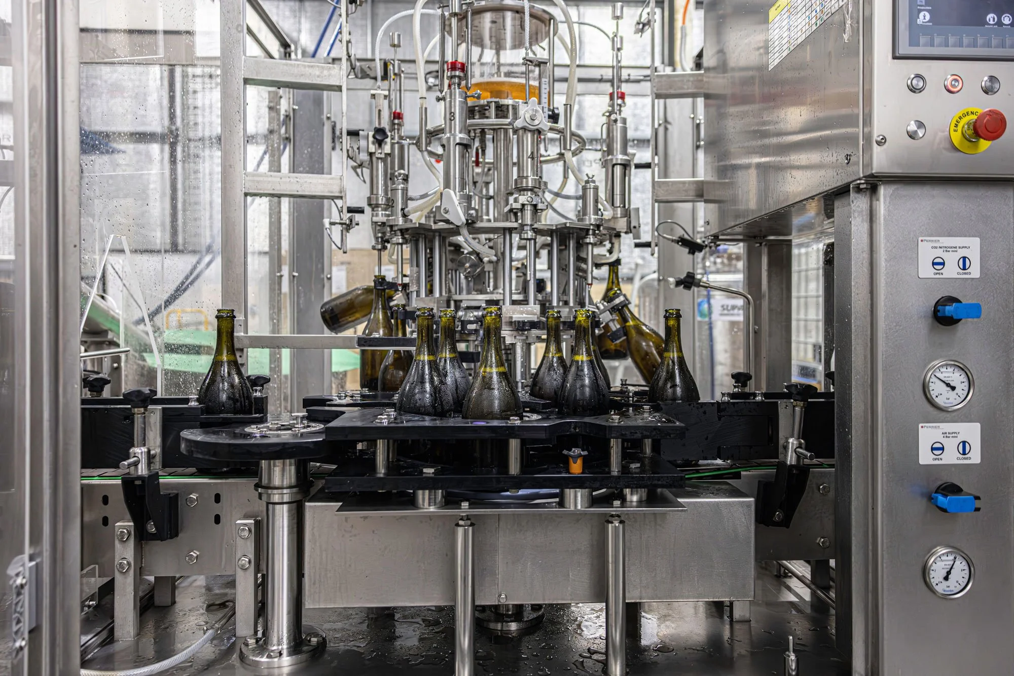 Industrial bottle filling machine in Kilchurn Wines factory, filling glass sparkling bottles with wine.