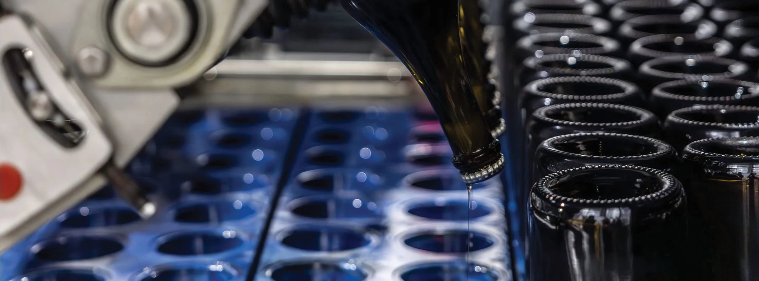 Kilchurn wines machinery preparing sparkling wine for vertical storage with lees sitting in the neck of bottles showing multiple bottles arranged in a tray.