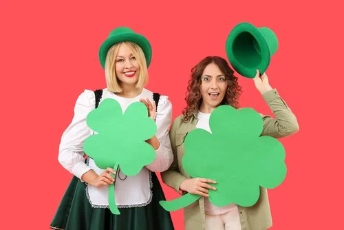 A cherry with a green stem and a mirrored disco ball heart on a bright pink background.