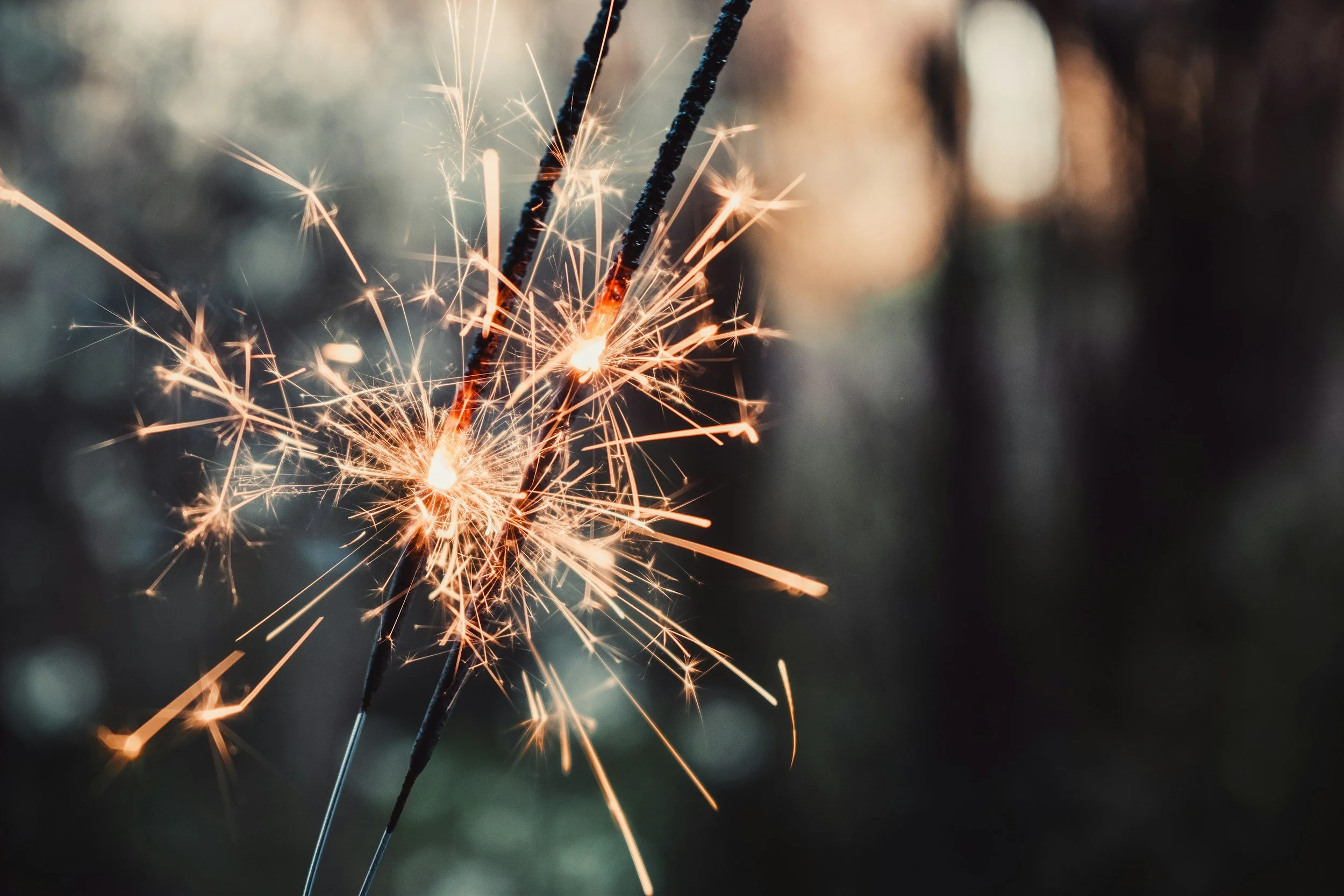 Close-up of a lit sparkler with bright sparks flying, dark blurred background. Image is used to promote CouplesTherapy.co social media pages with the handle @couplestherapy.co.