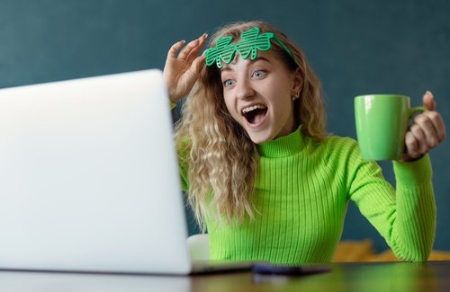 A young couple sitting on a leather sectional couch with a brick wall behind them, smiling and holding mugs, celebrating Christmas with holiday socks & decorations in the living room. Image is used for our CouplesTherapy.co Relationship Skills CLASS.
