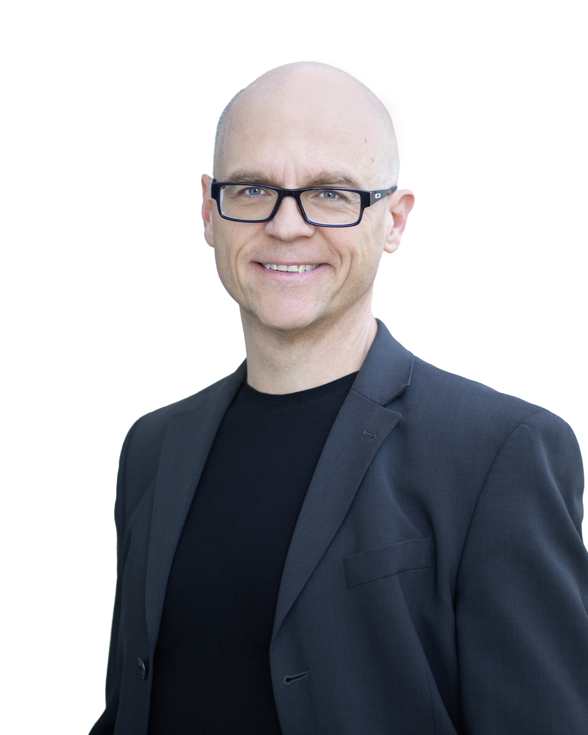 A man wearing glasses, a black shirt, and a black blazer smiling against a white background.