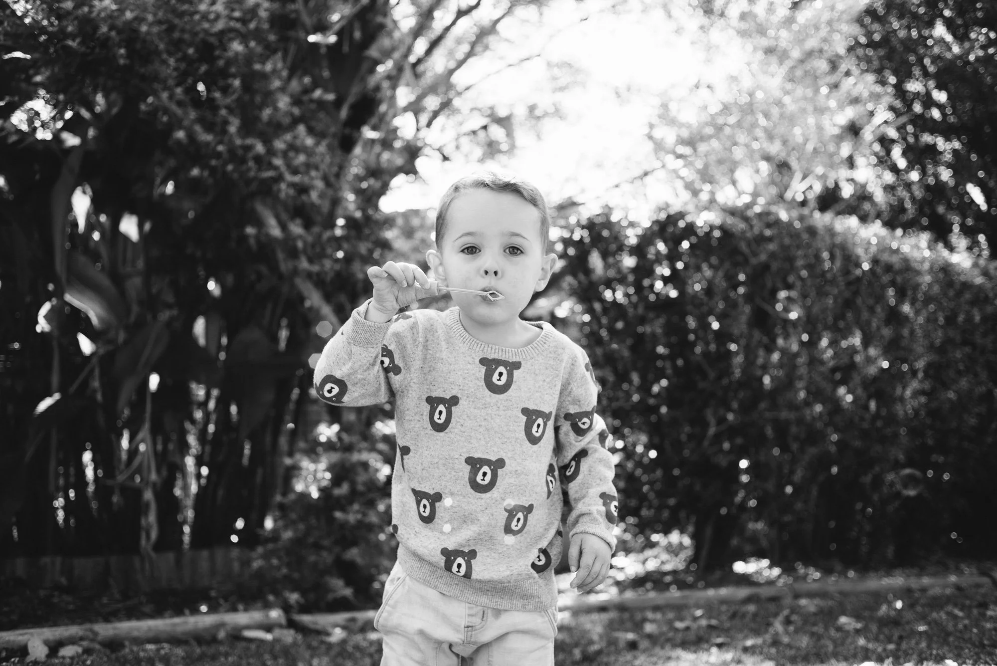 Black and white portrait photography of a boy blowing bubbles