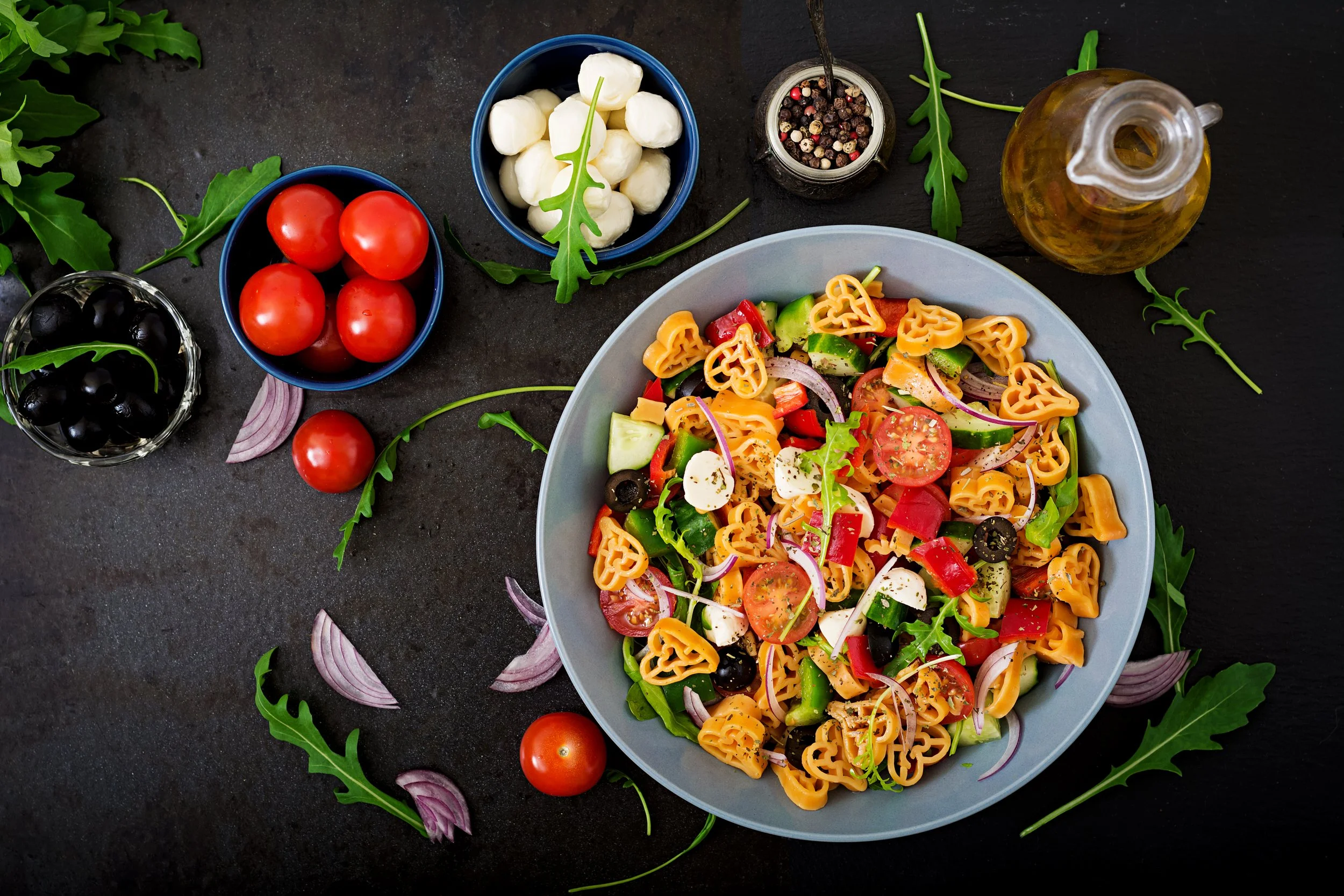 pasta-shape-heart-salad-with-tomatoes-cucumbers-olives-mozzarella-red-onion-greek-style-flat-lay-top-view.jpg