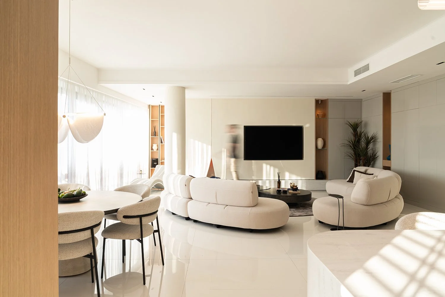 Ljust vardagsrum med platsbyggd förvaring och mjuka former.