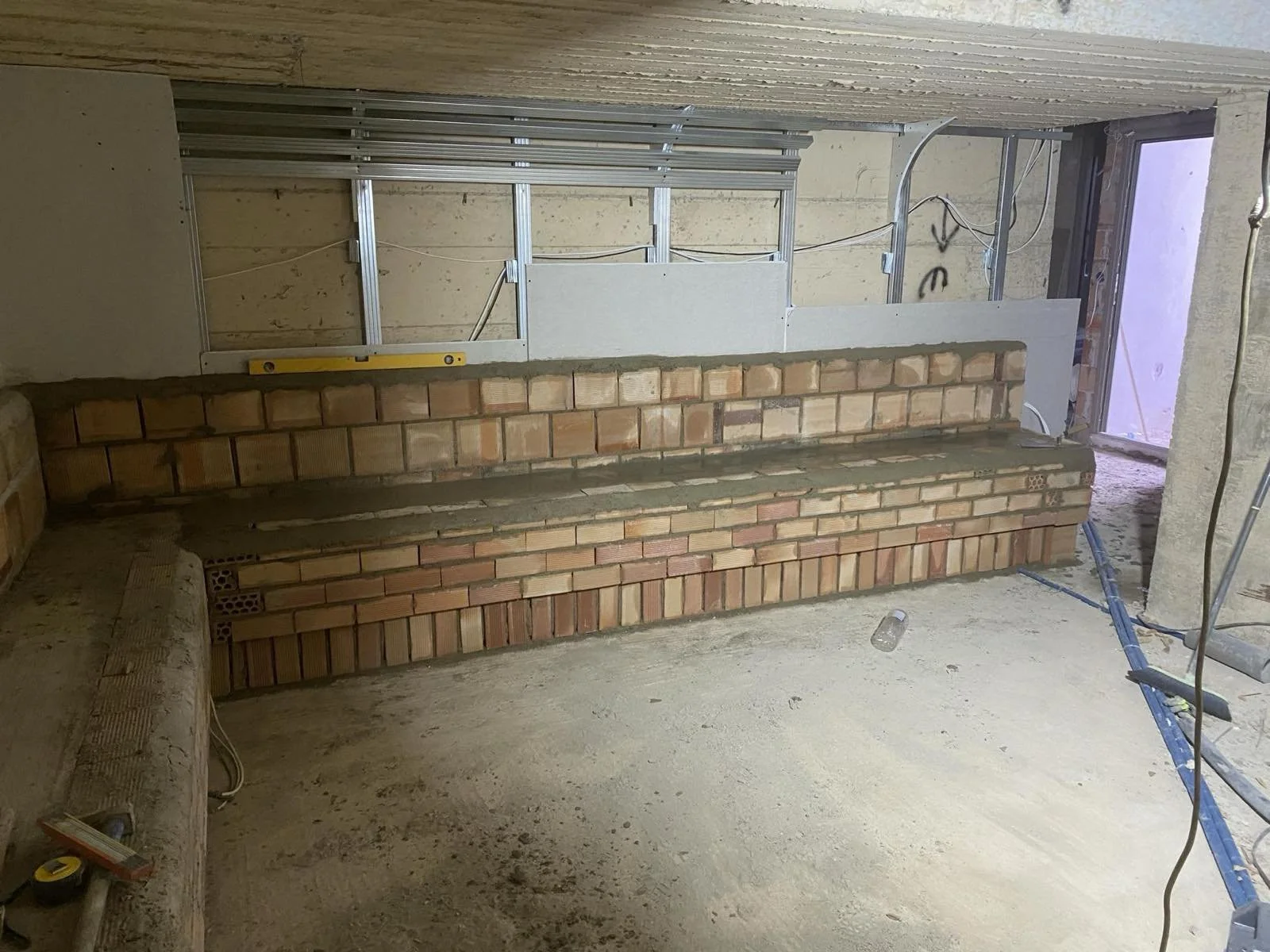 Construction site with brick wall and metal framing for interior renovation.