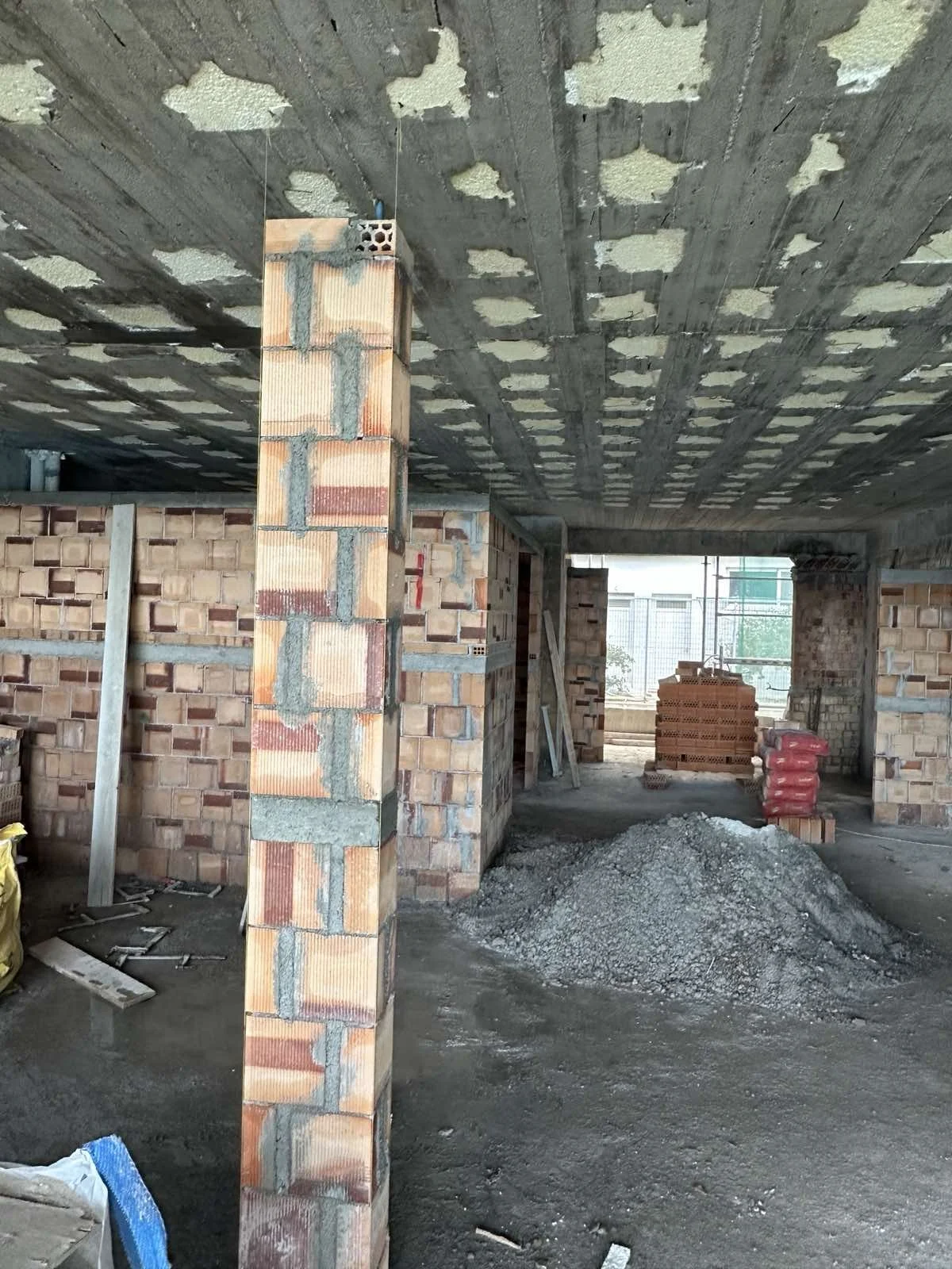 Construction site with brick walls, a pile of gravel, and an unfinished ceiling.