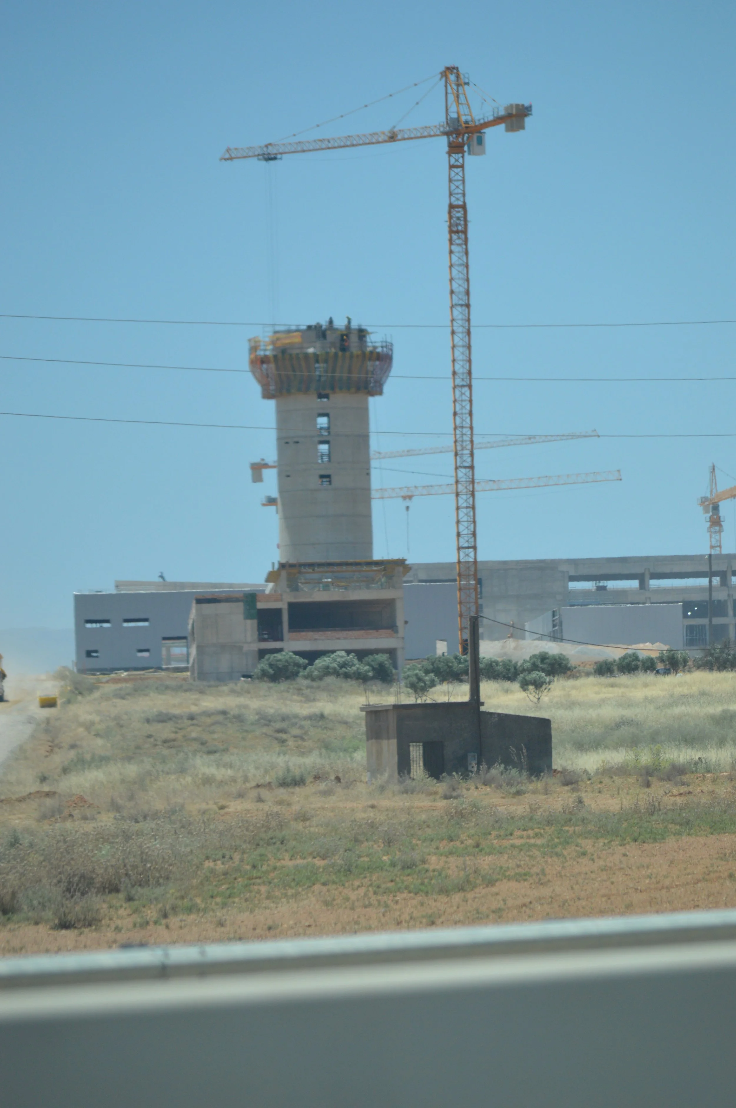 Construction site with a tall building under construction and multiple cranes around it.