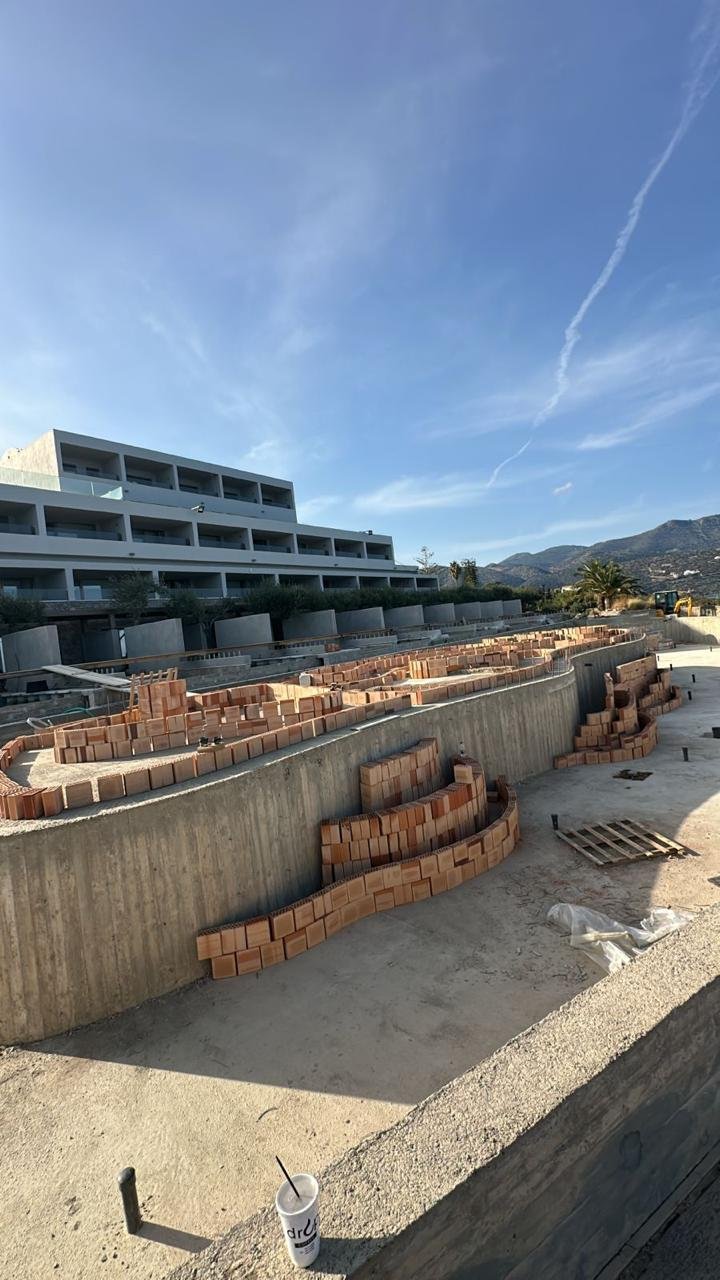 Construction site with building and curved brick wall under construction