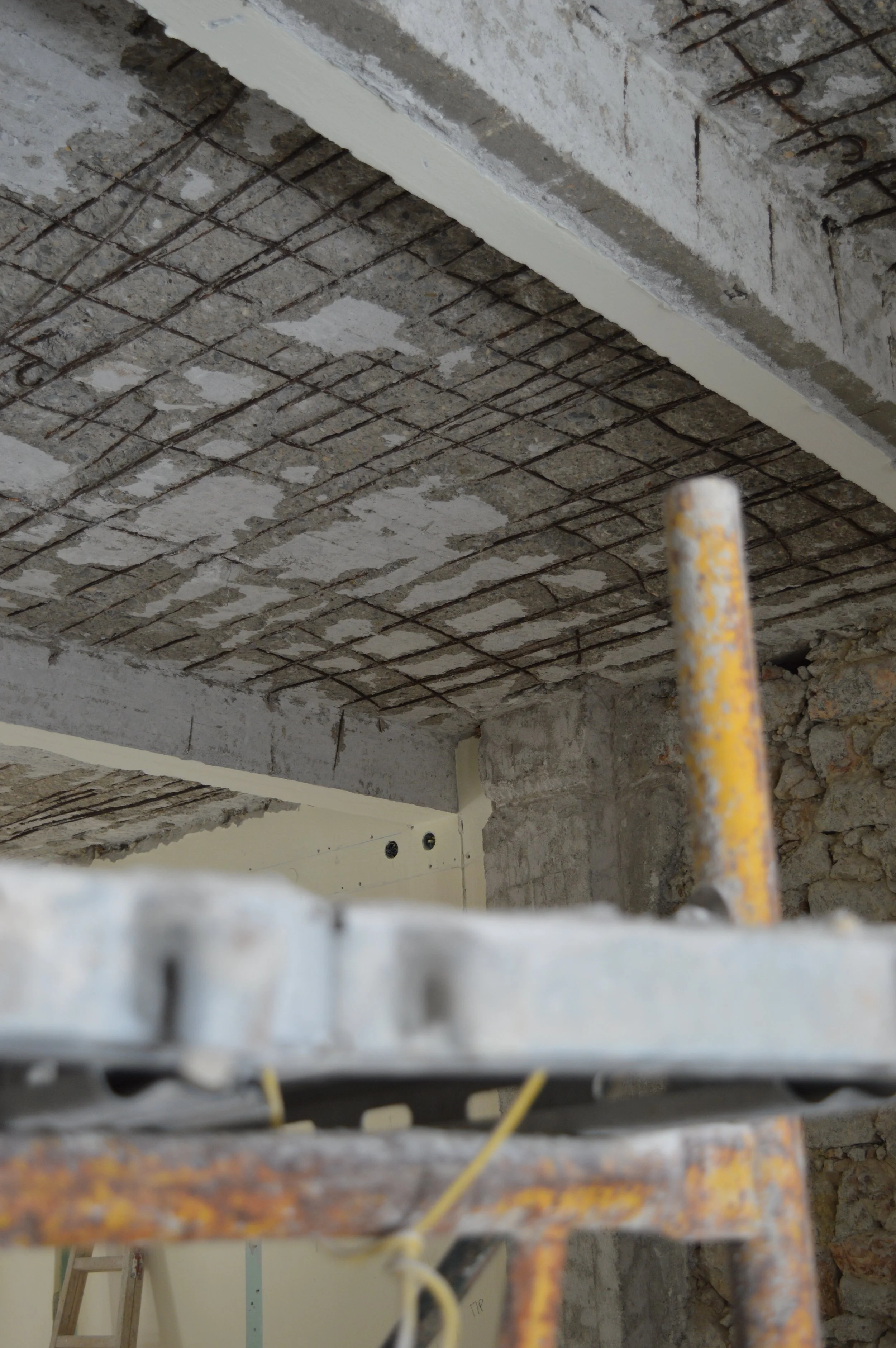 Construction site ceiling with exposed rebar and concrete.