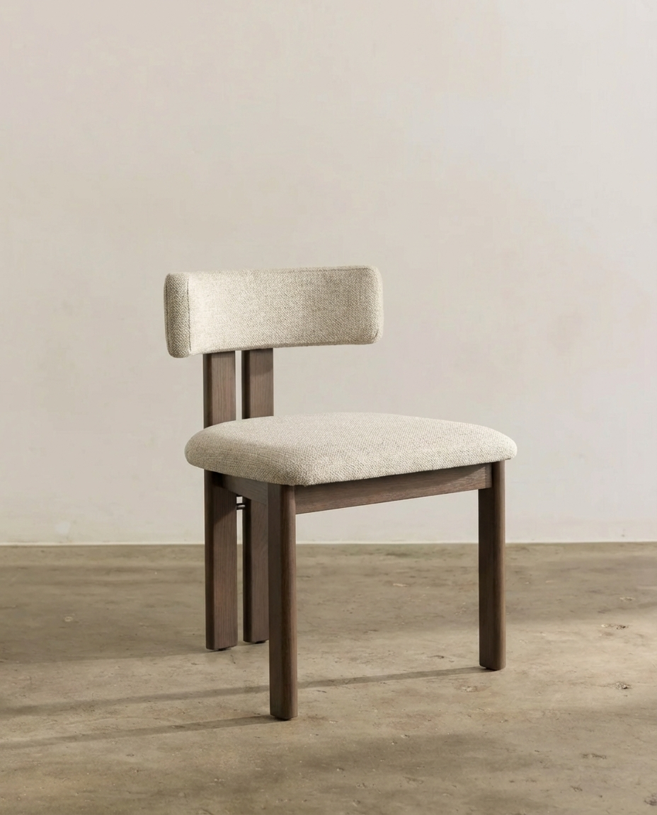 A modern wooden chair with beige cushioned seat and backrest, positioned against a plain white wall on a wooden floor.