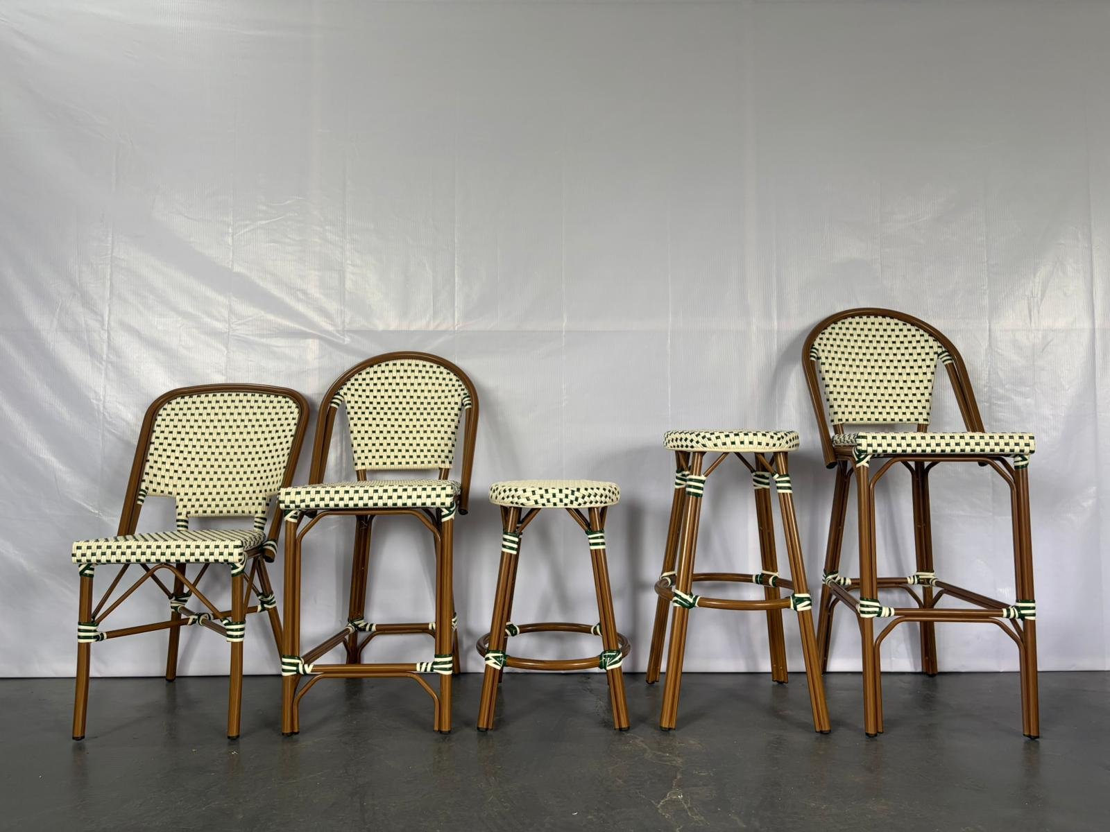 Six rattan chairs with woven seats and backs arranged against a plain white backdrop, with some chairs missing or replaced by a stool.