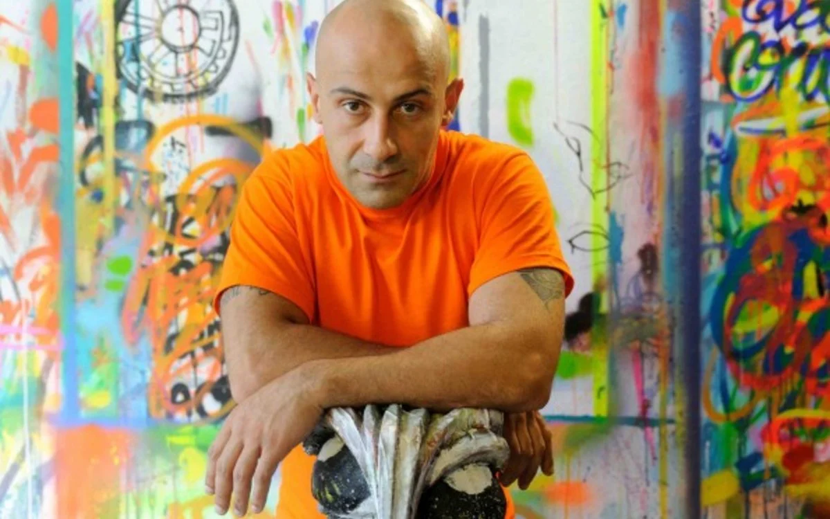 Un homme en t-shirt orange dans un espace rempli de graffiti coloré sur les murs.