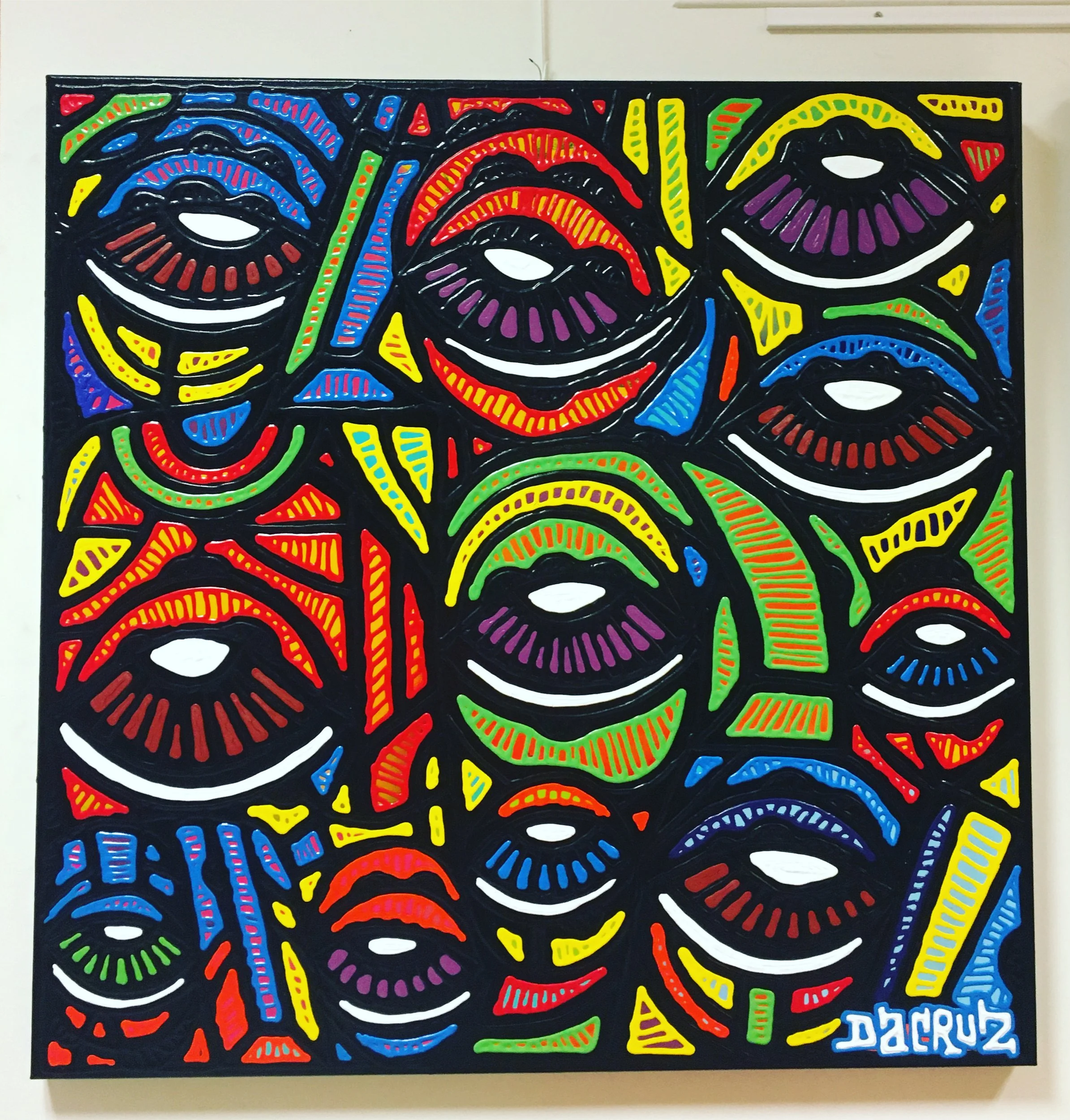 Une toile colorée représentant plusieurs yeux stylisés avec des contours noirs et des détails en rouge, vert, bleu, jaune et violet, créant un motif répétitif et vibrant.