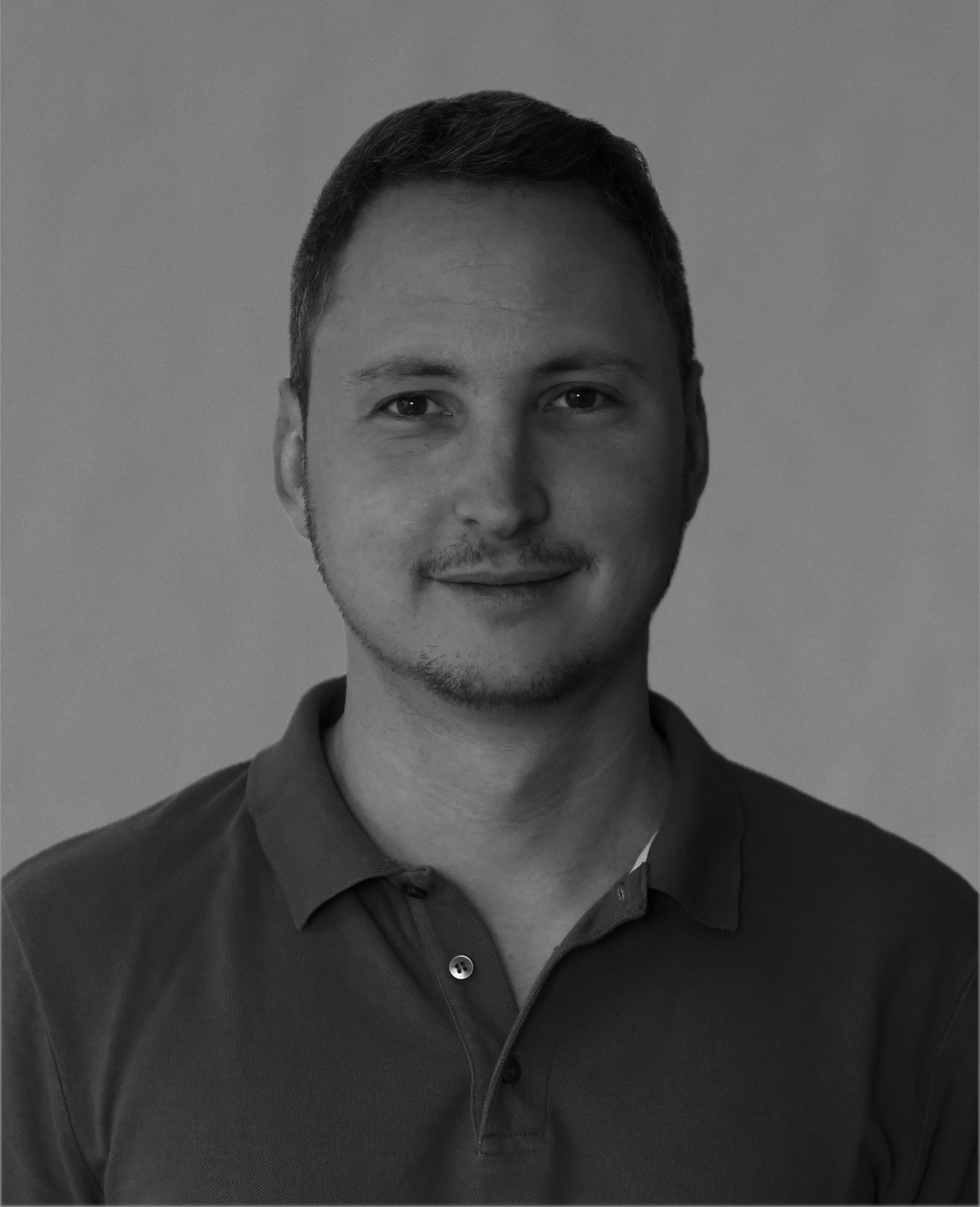 Portrait d'un homme jeune avec des cheveux courts, souriant en regardant l'appareil photo, portant une chemise à col.