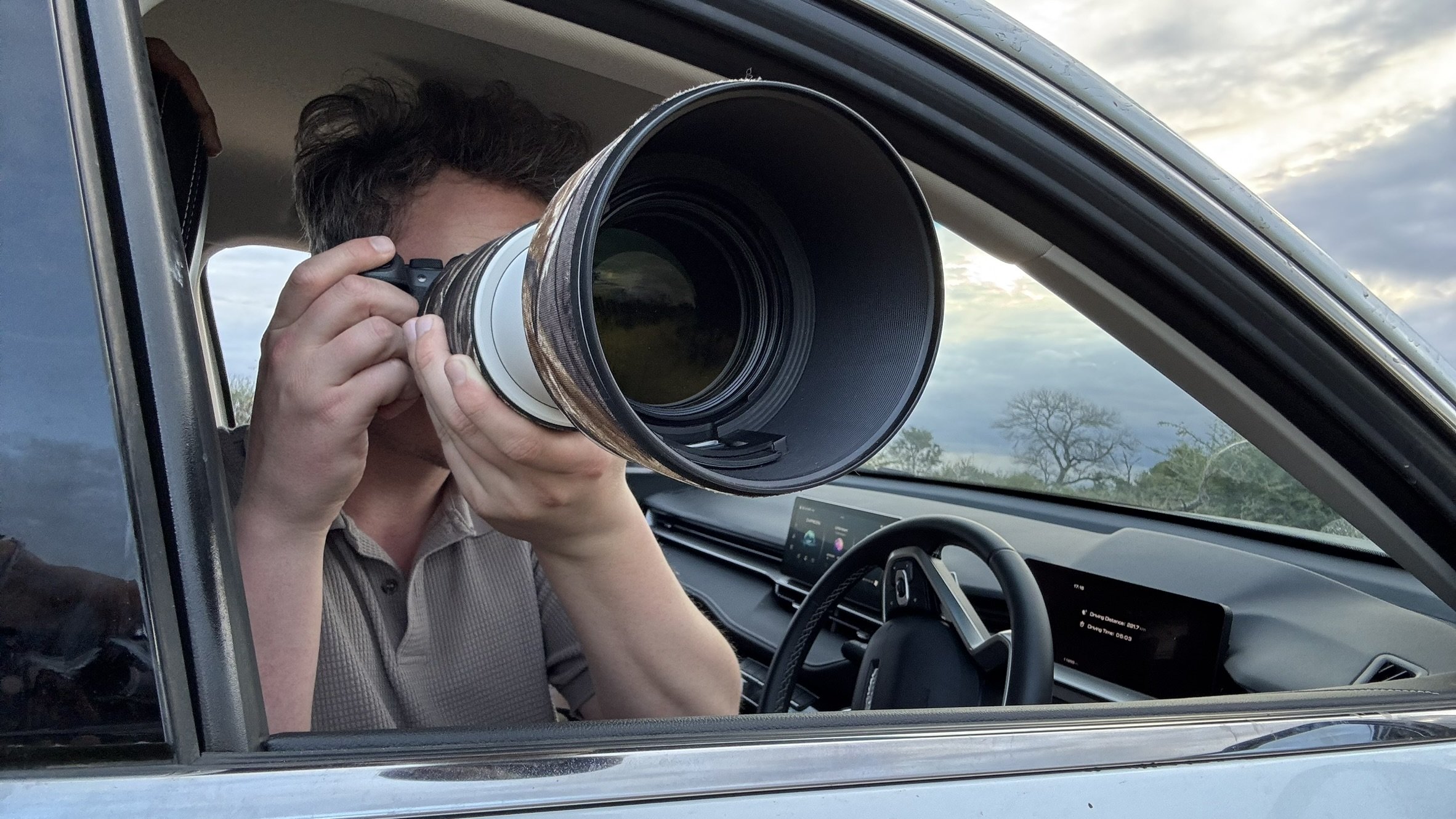 Un homme avec un appareil photo gros plan, pris de l'intérieur d'une voiture.