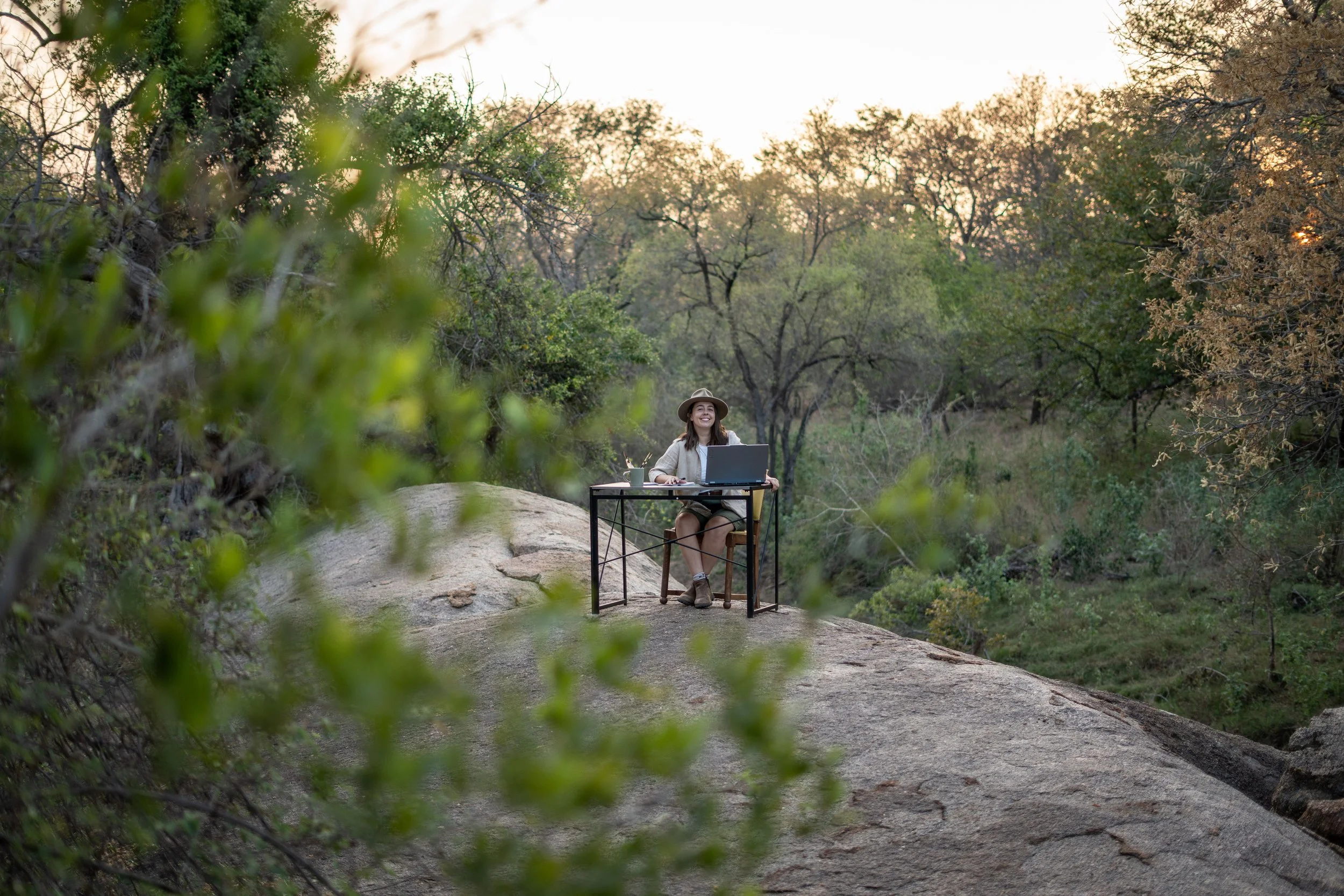 Rebecca siting at her desk on top of a rock