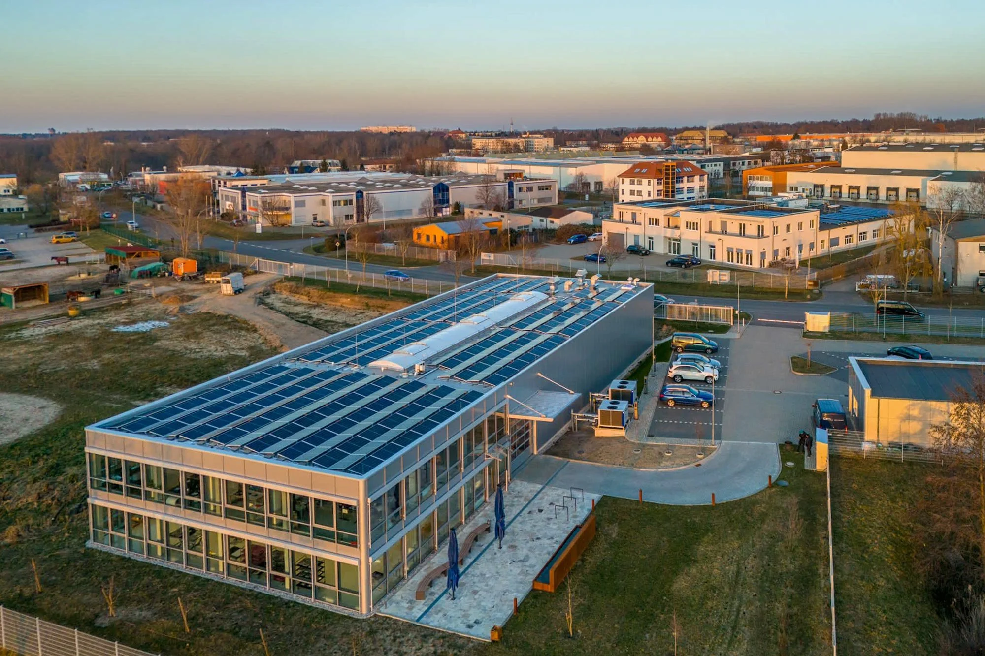 Halle mit großflächigem Glasdach und Solarpaneelen in einem Gewerbegebiet