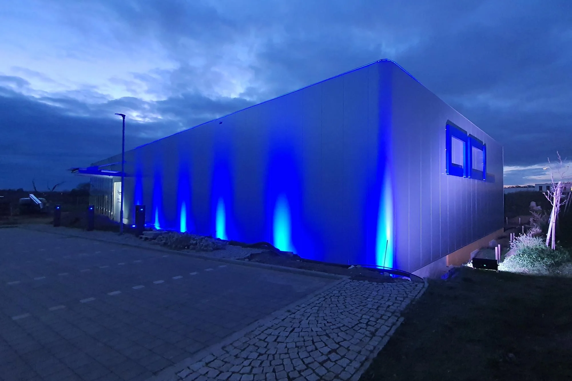 Industriehalle mit blauer LED-Beleuchtung an der Fassade und seitlichen Fenstern