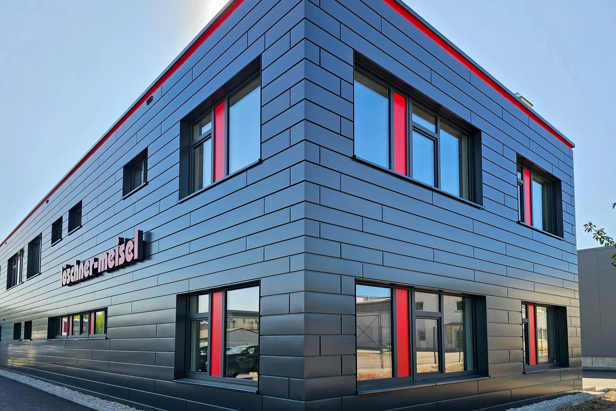 Schwarze Fassadenverkleidung mit roten Farbakzenten und präziser Linienführung