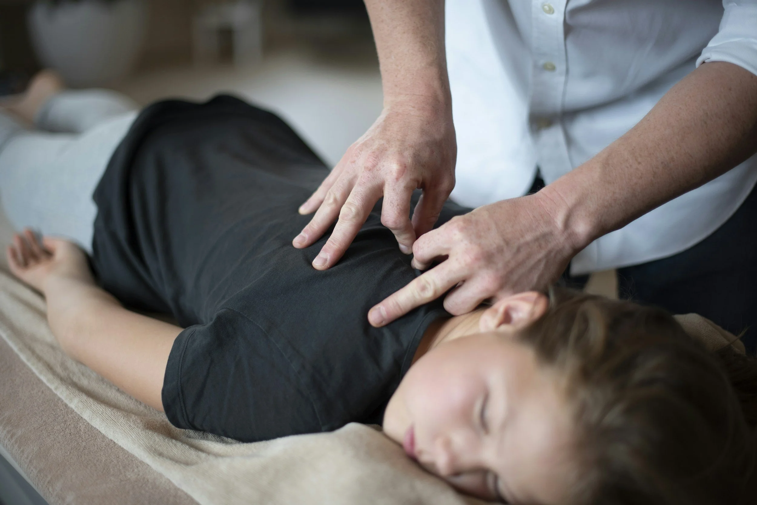 Eine Person erhält eine professionelle Rückenmassage auf einer Massagebank im Therapieraum.