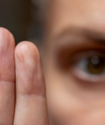 Close-up of a person's eye and hand near their face.