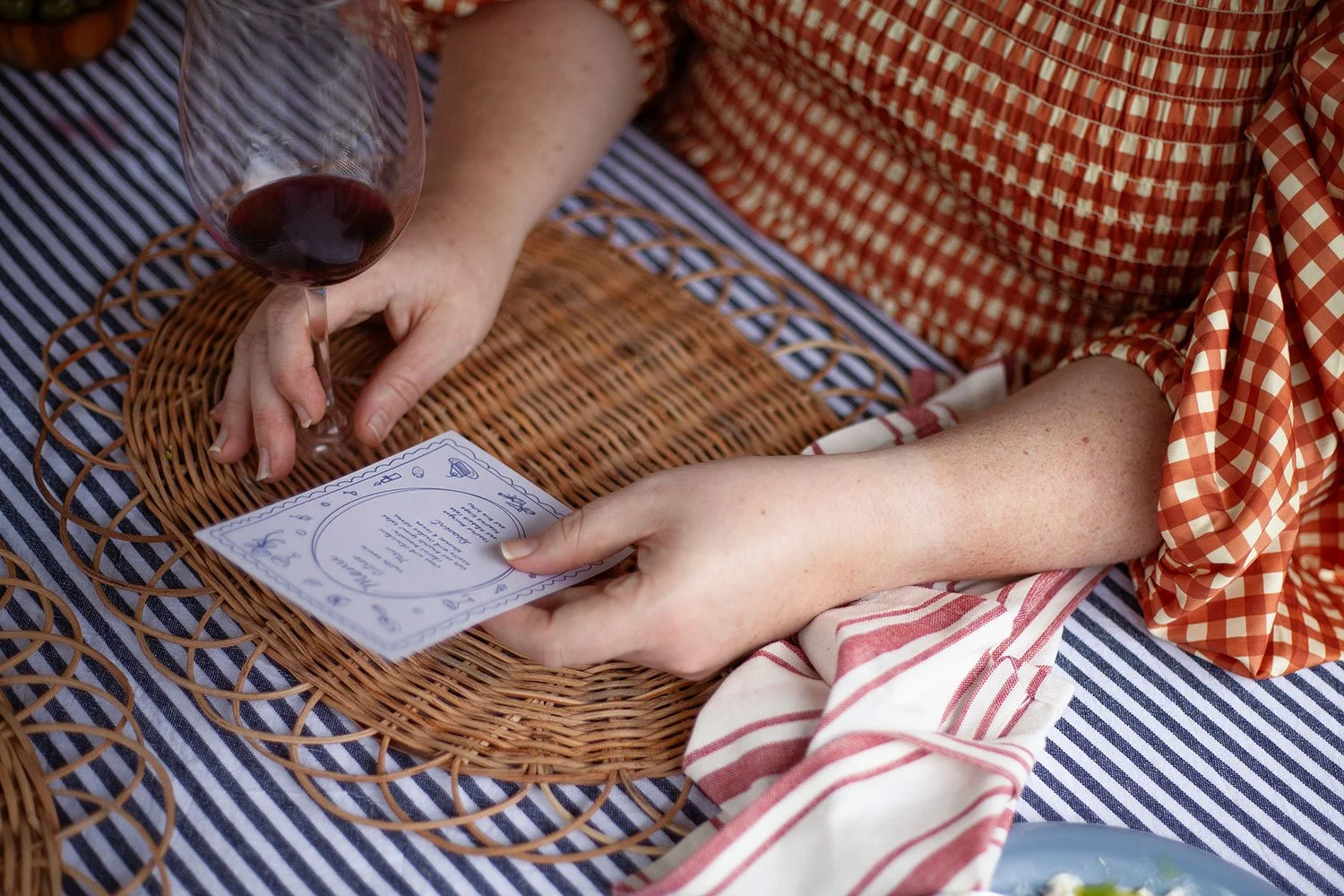 person sitting at a table with a glass of red wine reading a menu for a dinner party