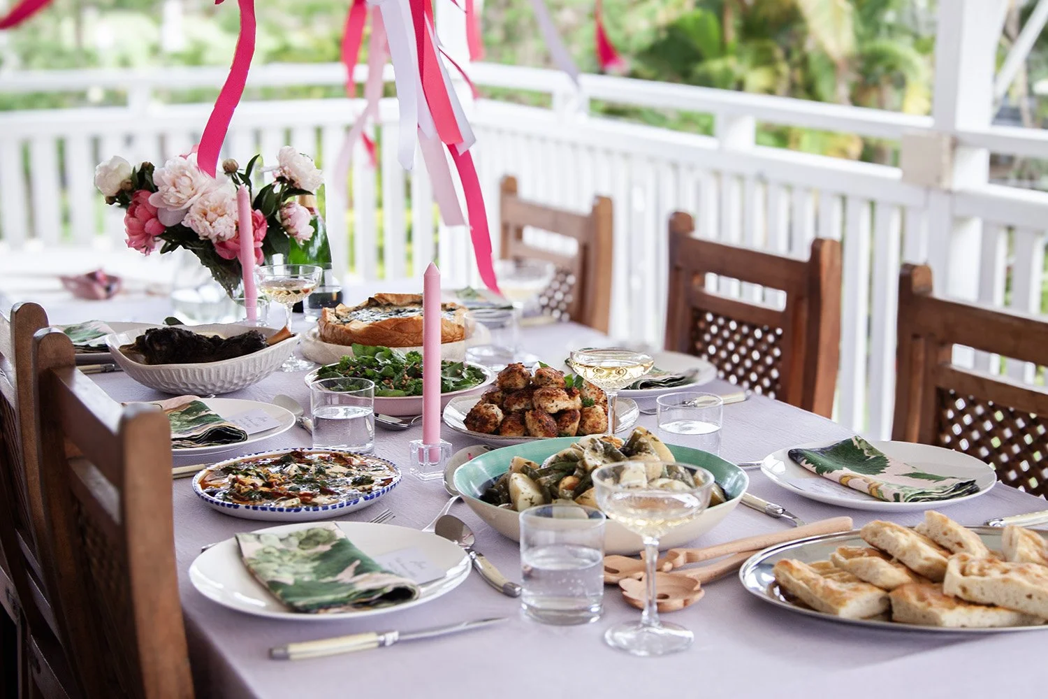table setting filled with food and champagne pink streamers coming from the roof and pink peonies on the table