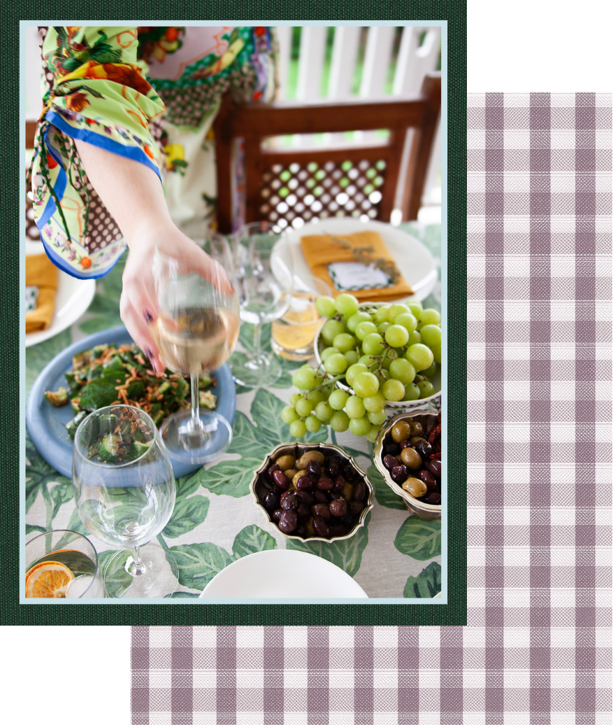 Person picking up white wine glass on a table full of food