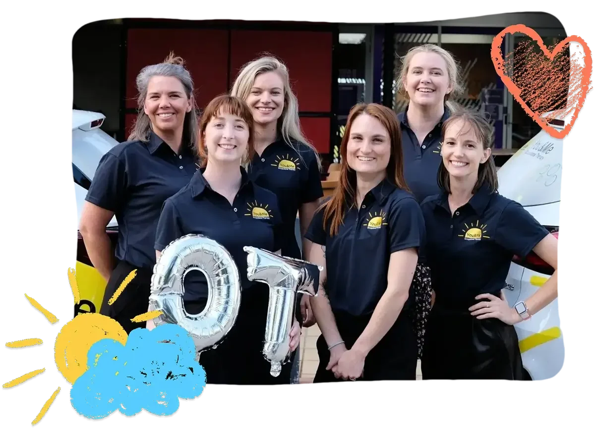 A group of six smiling women wearing black shirts with a yellow logo, standing outdoors in front of vehicles, holding silver balloons forming the number 01, with added colorful drawings of a sun, cloud, and a heart.