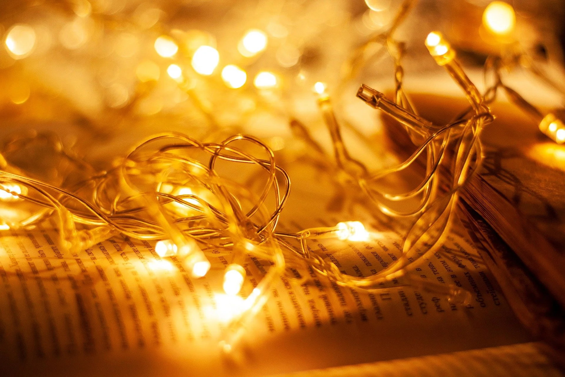Close-up of a string of warm yellow fairy lights resting on an open magazine or newspaper.