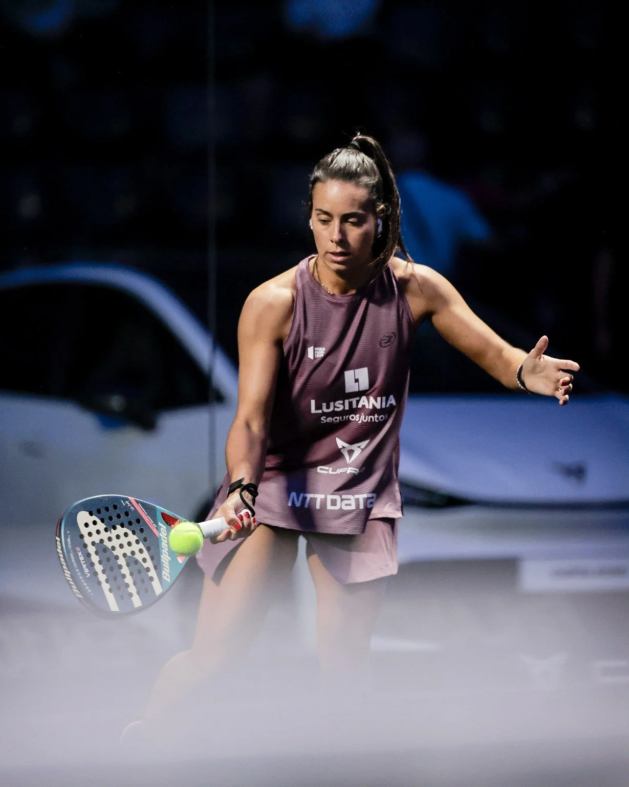 Female padel player hitting a ball during a match.