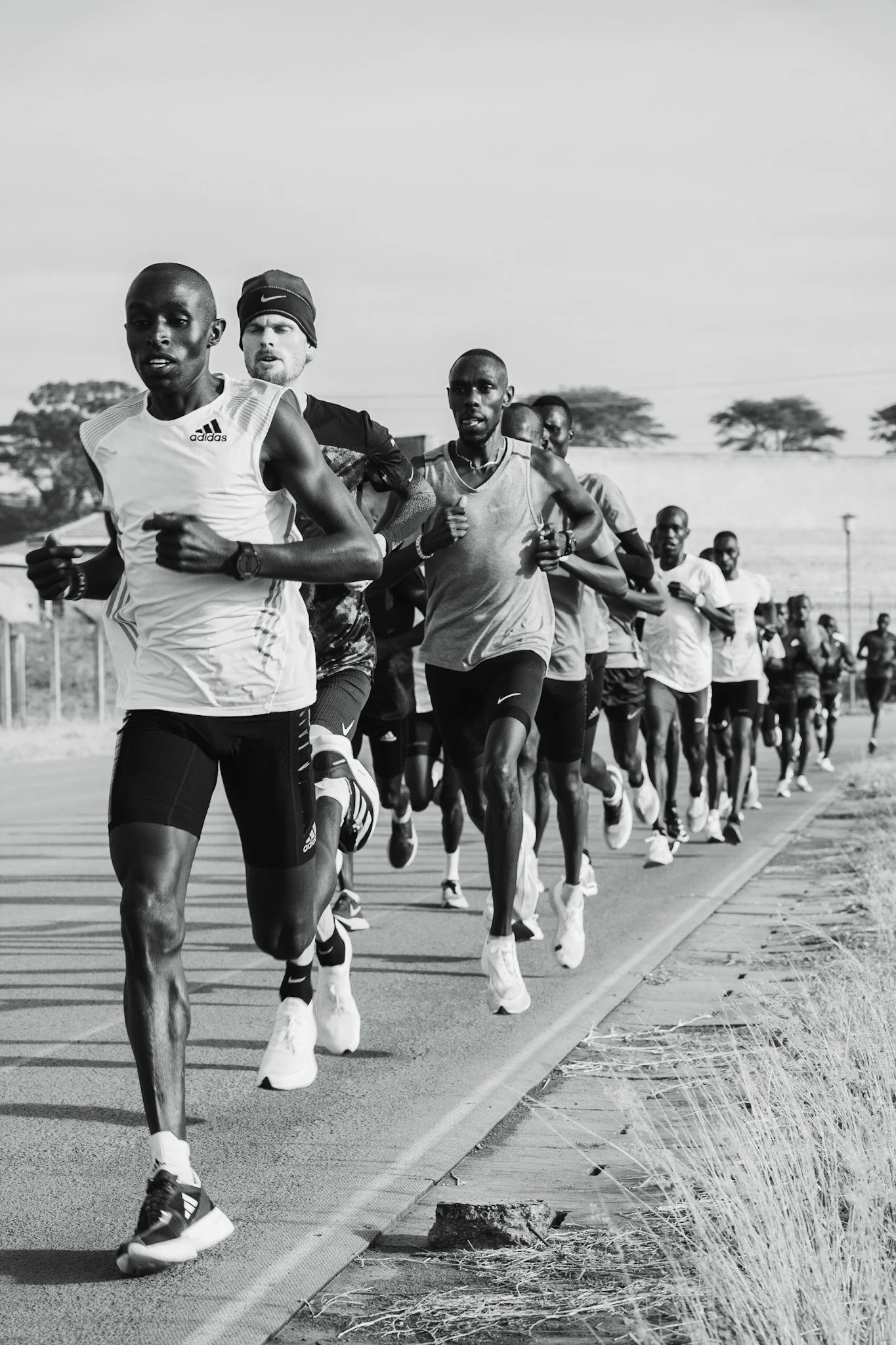Groupe de coureurs lors d'une course en extérieur, vue en noir et blanc.