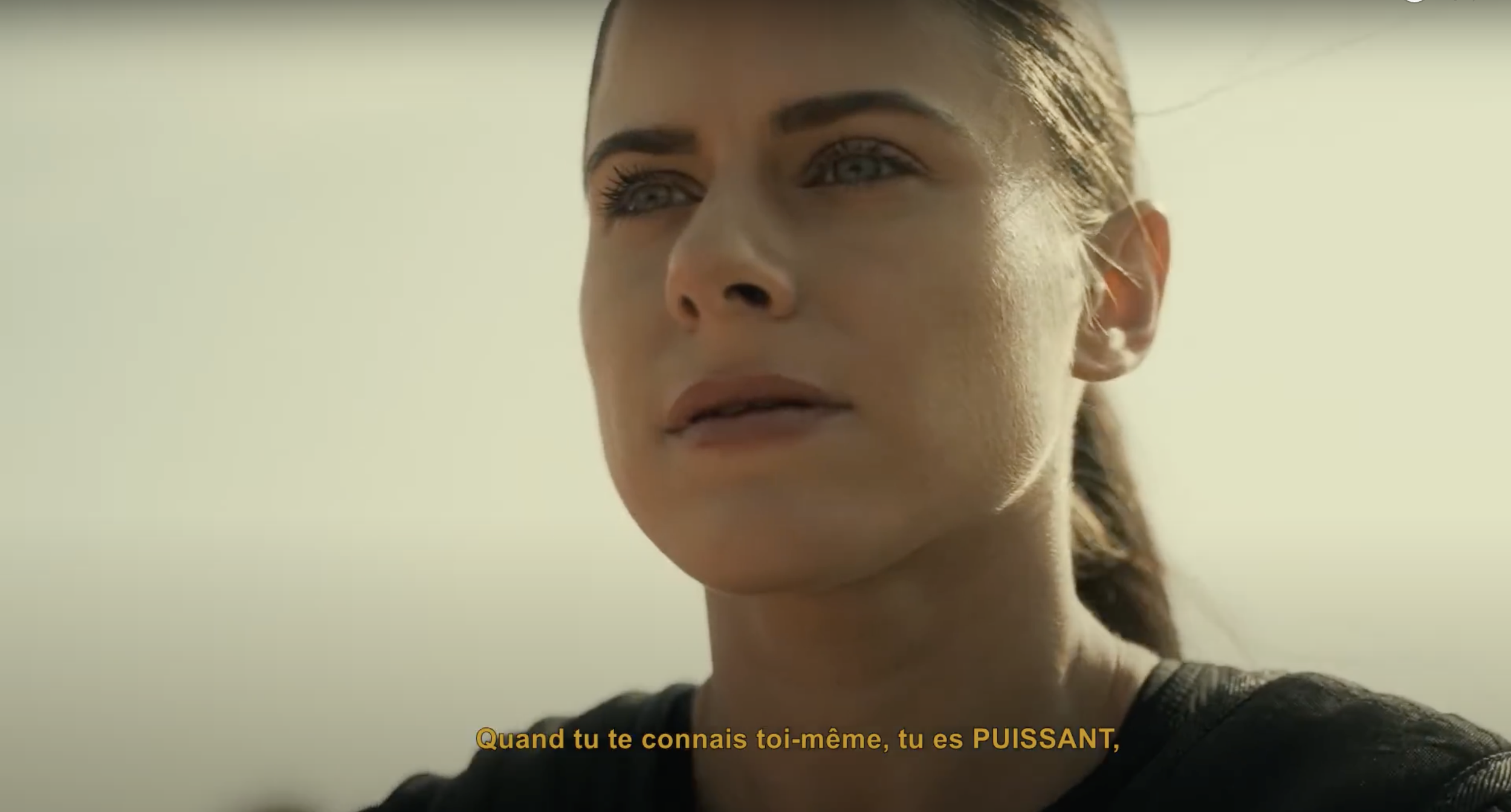 Une femme regarde pensivement avec un fond lumineux, commentaires en français en bas de l'image.